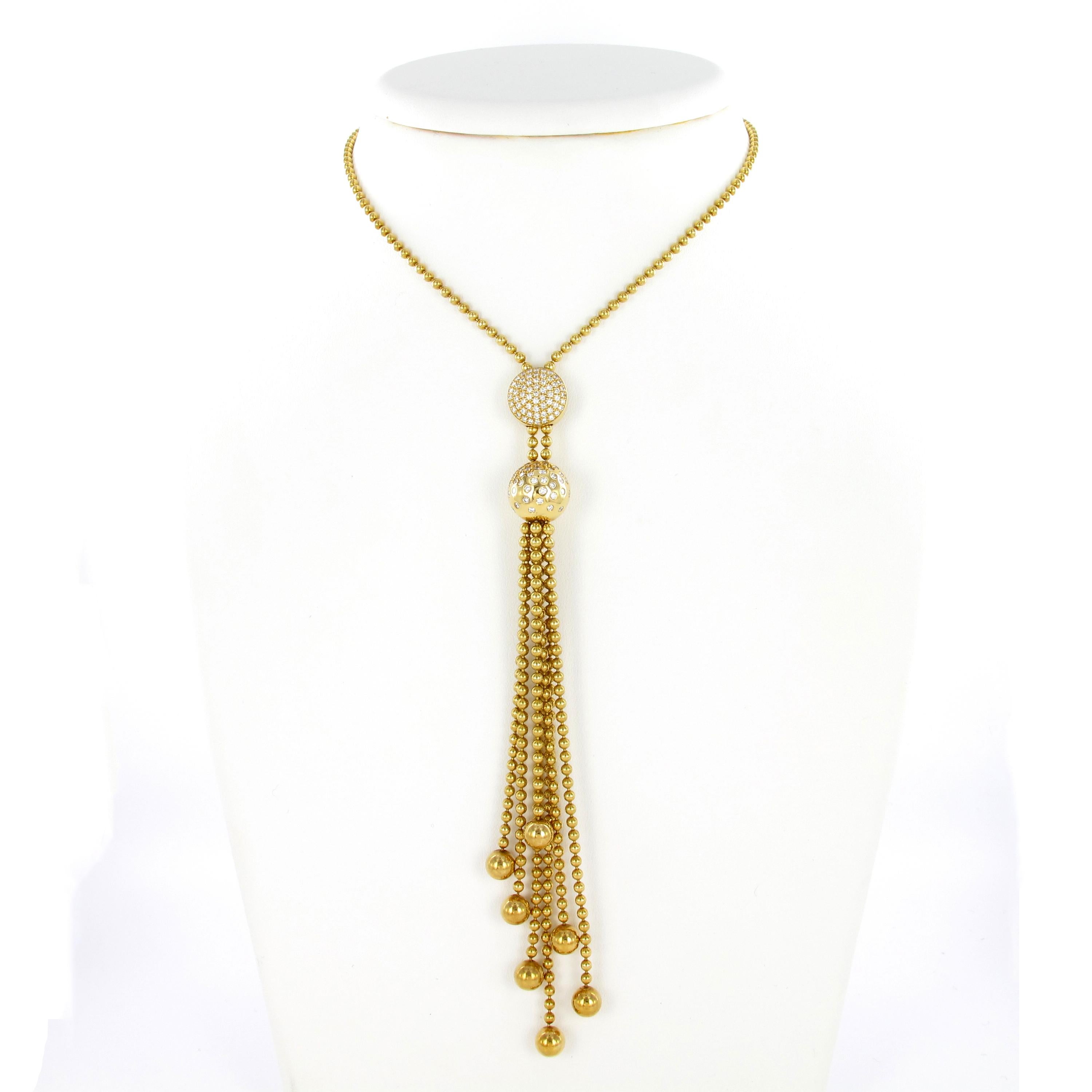 This Cartier necklace from the Perruque Collection is set with a gold sphere accented by brilliant cut diamonds suspending a tassel of gold beads. Length can be adjusted with a circular diamond-set plaque, mounted in 18 karat yellow gold. Total