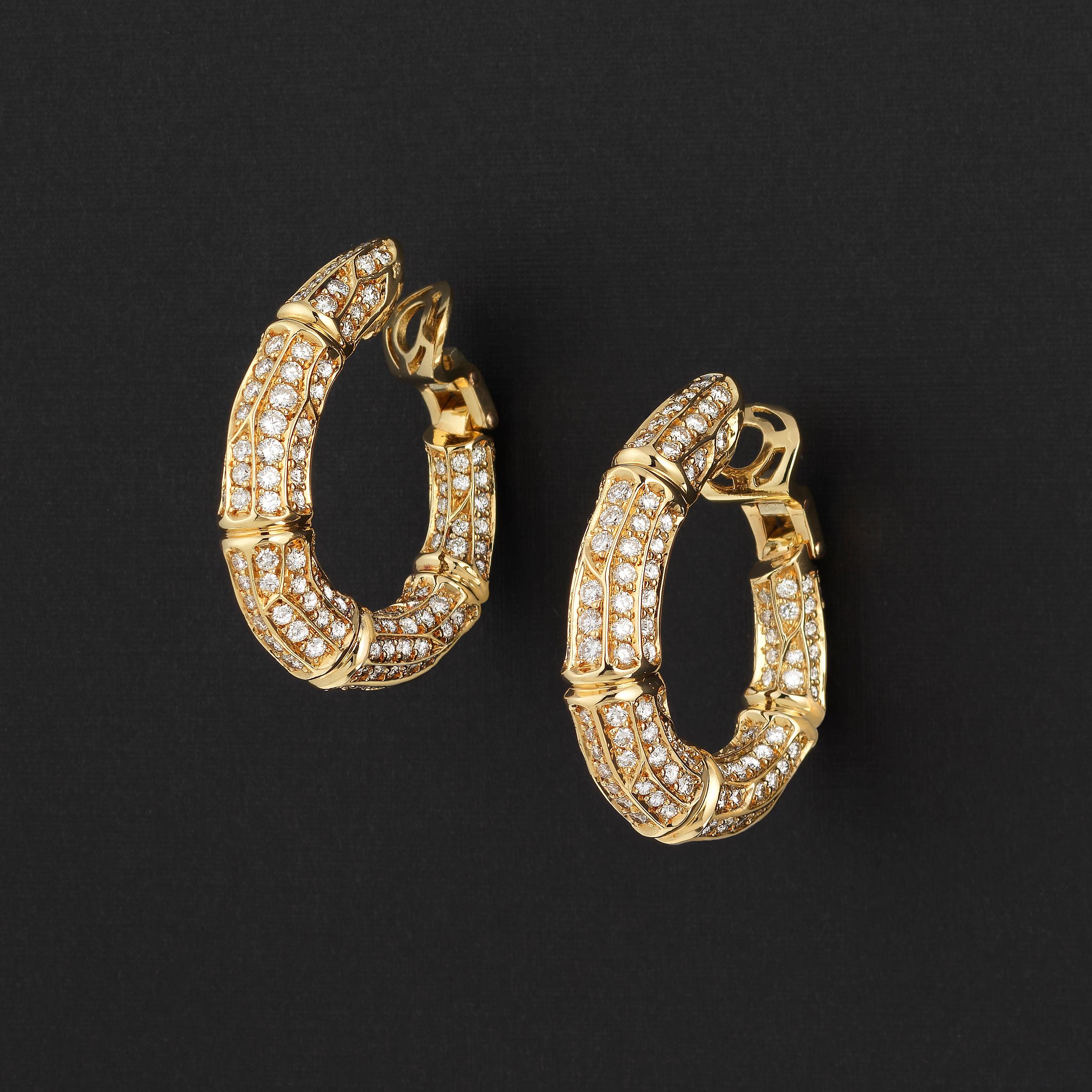 Dazzling vintage Cartier Bamboo earrings showcasing approximately 6 carats of fine-white brilliant round diamonds impeccably set in lustrous 18 karat yellow gold. The hoop-type earrings are wonderfully balanced when worn, and even their inner-facing