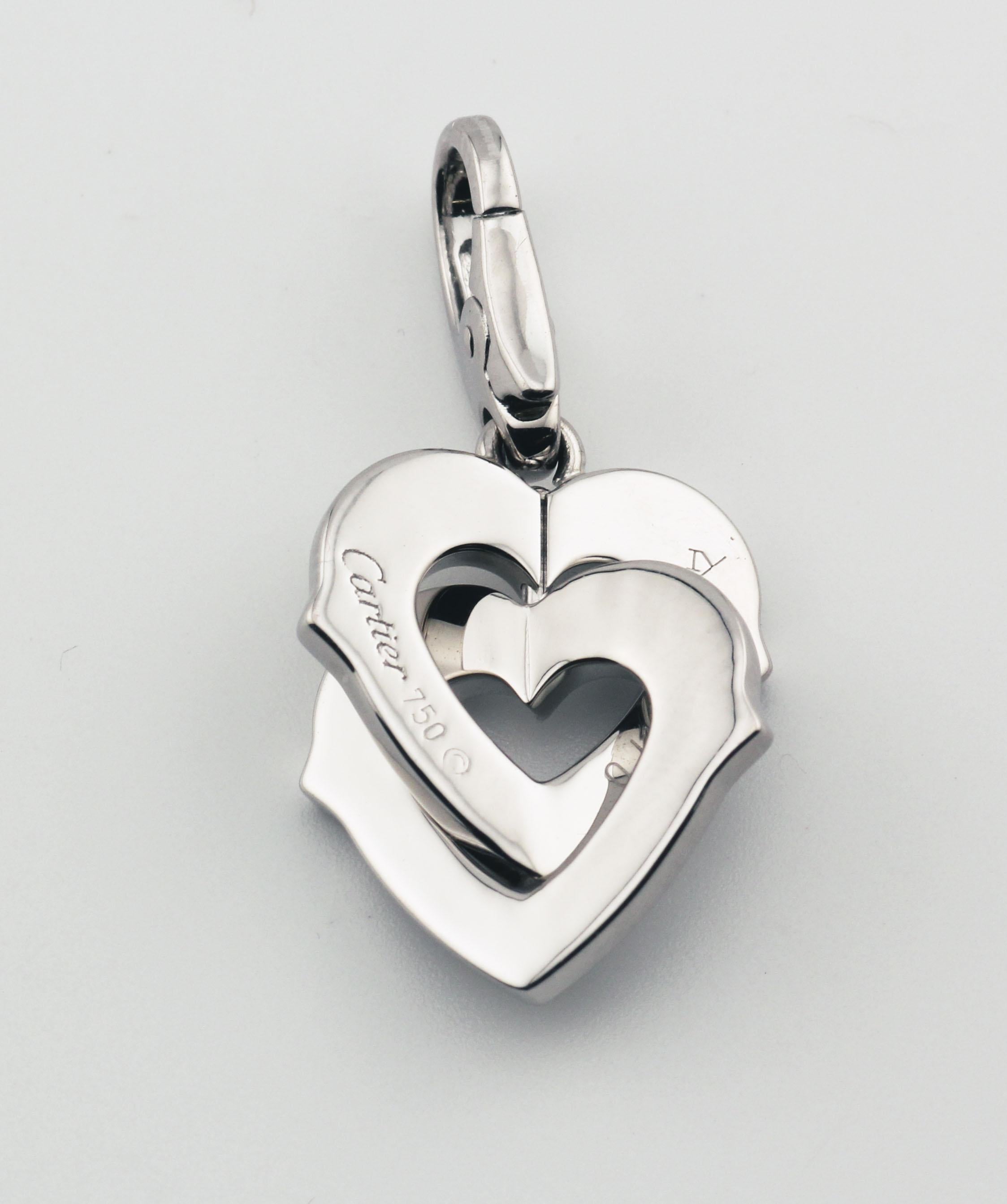 The Cartier Diamond 18K White Gold Double Heart Logo Charm Pendant is a romantic and elegant piece that captures the essence of love and luxury. Crafted from exquisite 18k white gold, this pendant features a delicate double heart design, intertwined