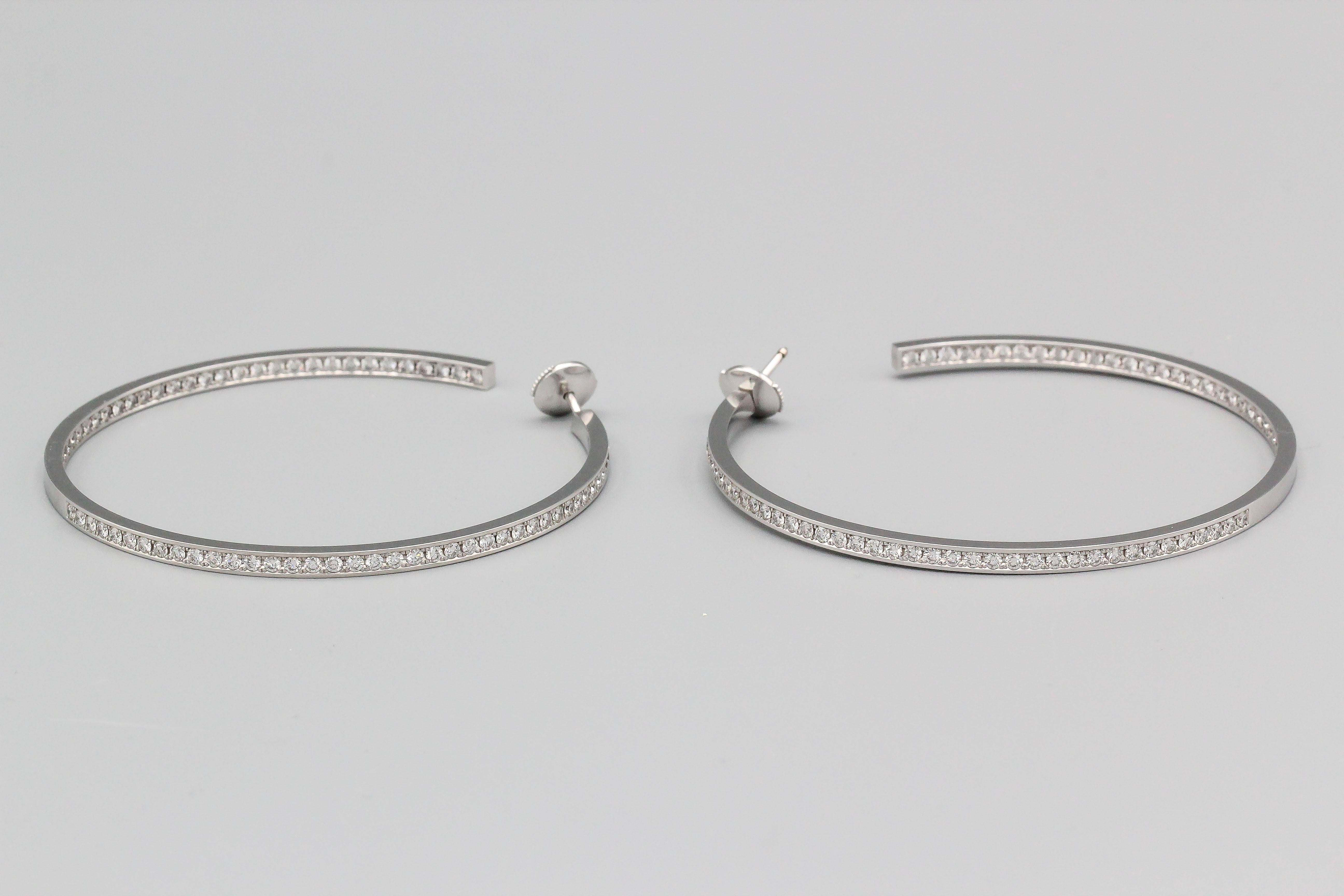 Beautiful 18K white gold and diamond hoop earrings by Cartier. They feature an 