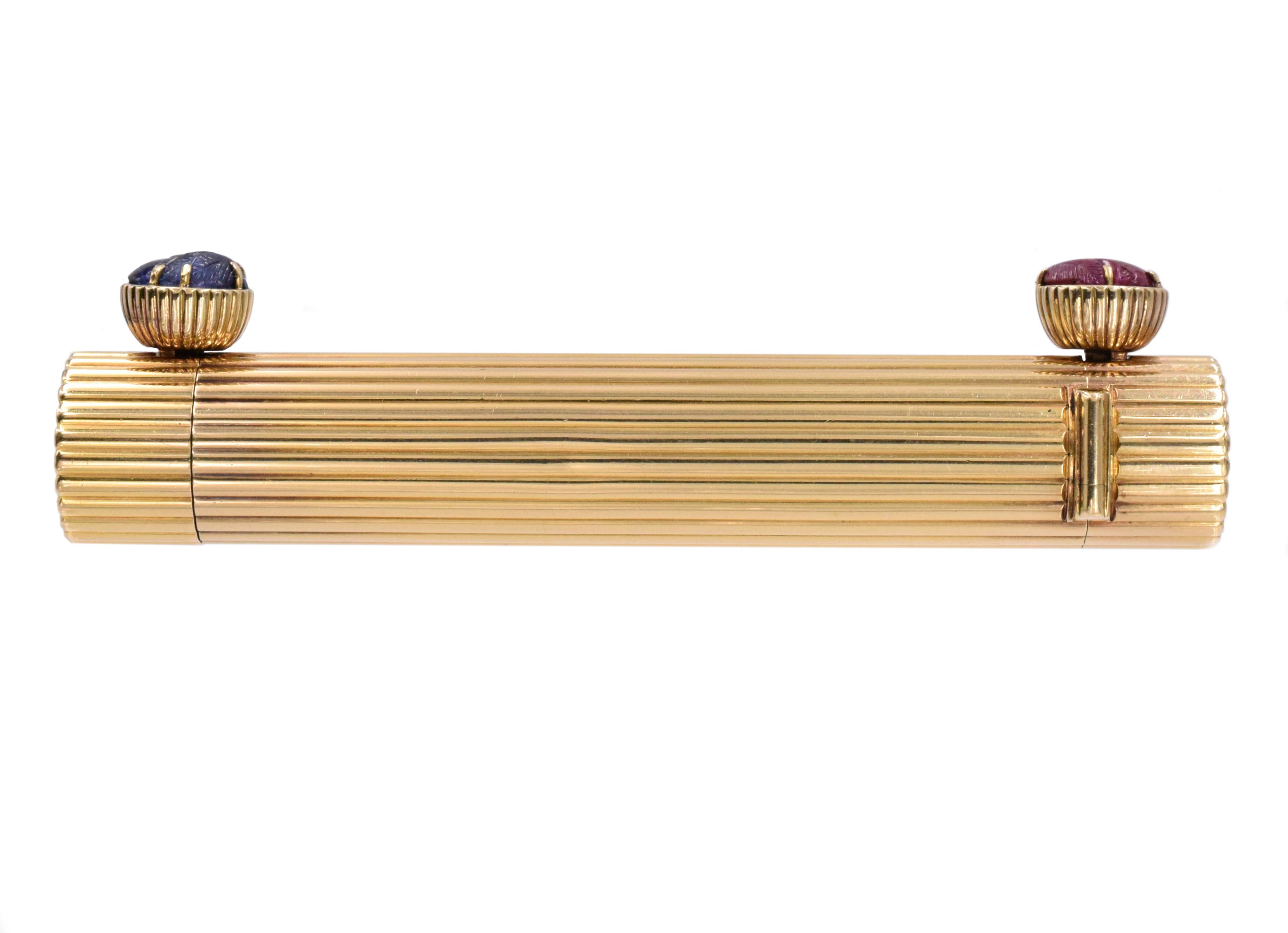 Cartier Double Headed Lipstick Holder This accessory has two heads that can hold lipstick and 2 carved gemstones (ruby and sapphire) all set in 18k yellow gold. Signed Cartier Paris, 750, maker mark and french assay marks. Measurements: 4 inches X
