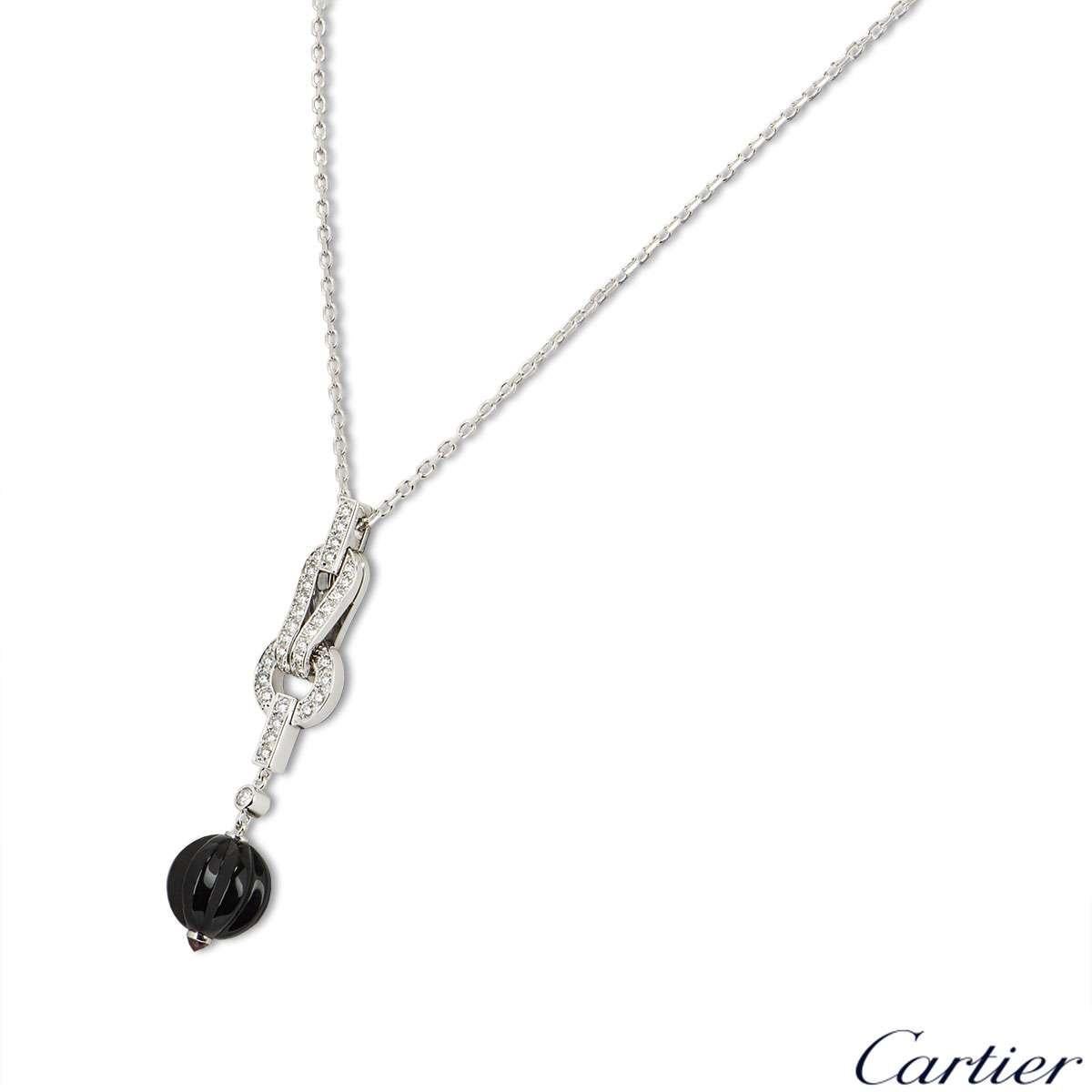 An 18 Carat white gold necklace from the Agrafe collection by Cartier. The necklace features the iconic Agrafe motif set with round brilliant cut diamonds. Suspended beneath the motif is a carved onyx ball measuring 11mm and a rubelite termination.