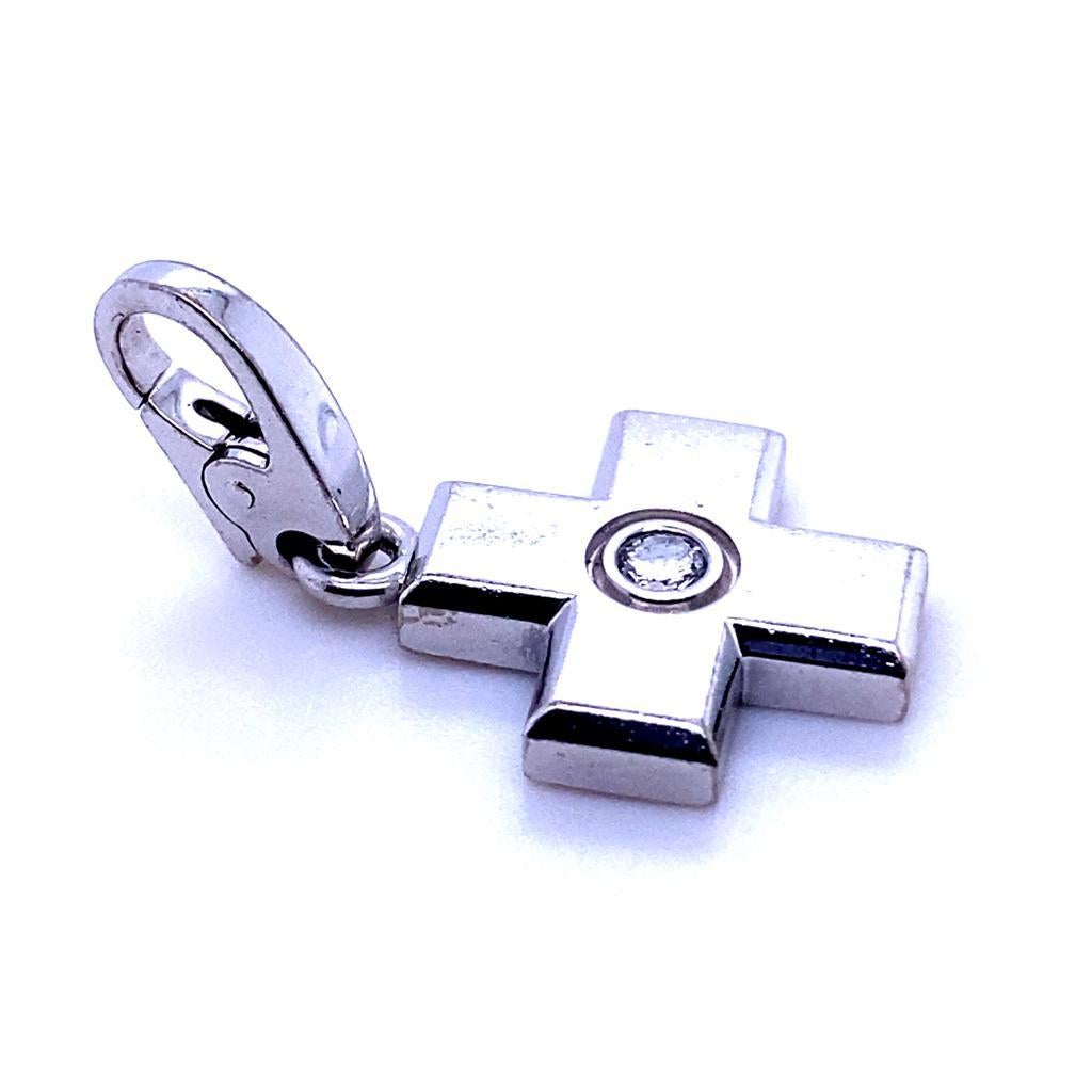 A Cartier diamond cross charm in 18 karat white gold.

This sweet 18 karat white gold charm was created by Cartier for their charm collection to enhance either their bracelets or necklaces. 

With a semi-matt finish the charm is bezel set to its