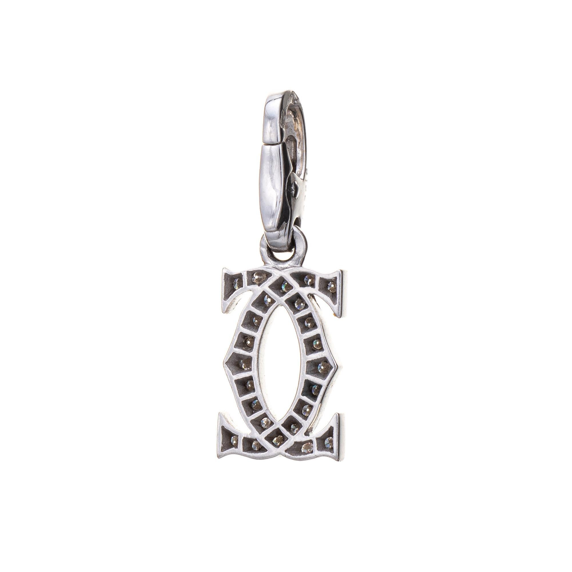 Cartier double C charm (or pendant), crafted in 18 karat white gold.  

Round brilliant cut diamonds total an estimated 0.21 carats (estimated at F-G color and VVS2 clarity). 
The petite double C logo charm is set with shimmering diamonds, great for