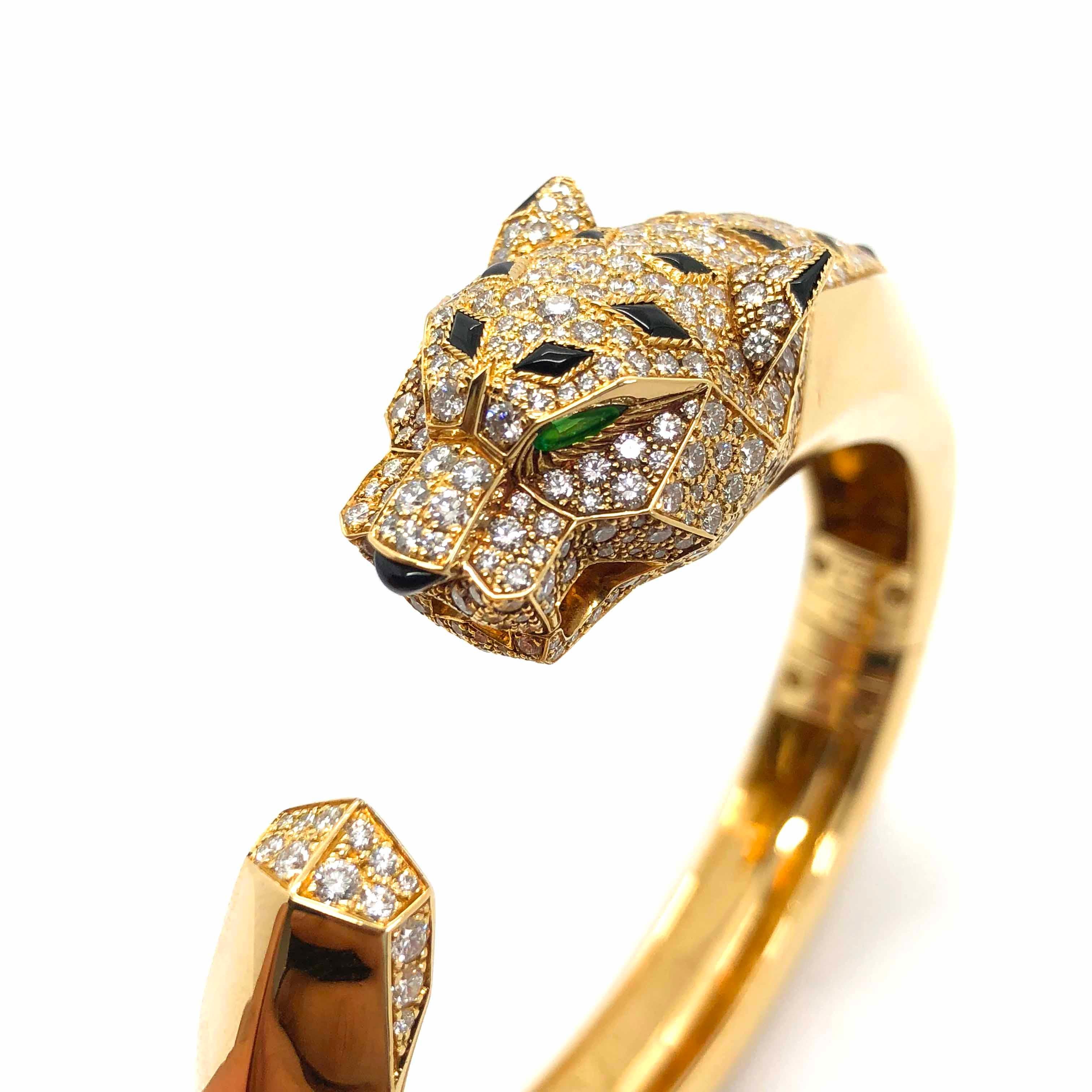 A stunning bangle in 18k yellow gold by Cartier. It is part of Cartier's Panthere collection symbolising a strong and independent woman. The eyes of the Panthere are made out of emeralds and the body is studded with diamonds and onyx in yellow gold.