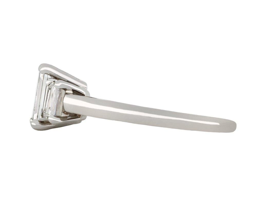 Cartier diamond flank solitaire ring. Set to centre with a rectangular step-cut diamond in an open back claw setting, with an approximate weight of 0.95 carats, flanked by two rectangular baguette cut diamonds in open back claw settings with a