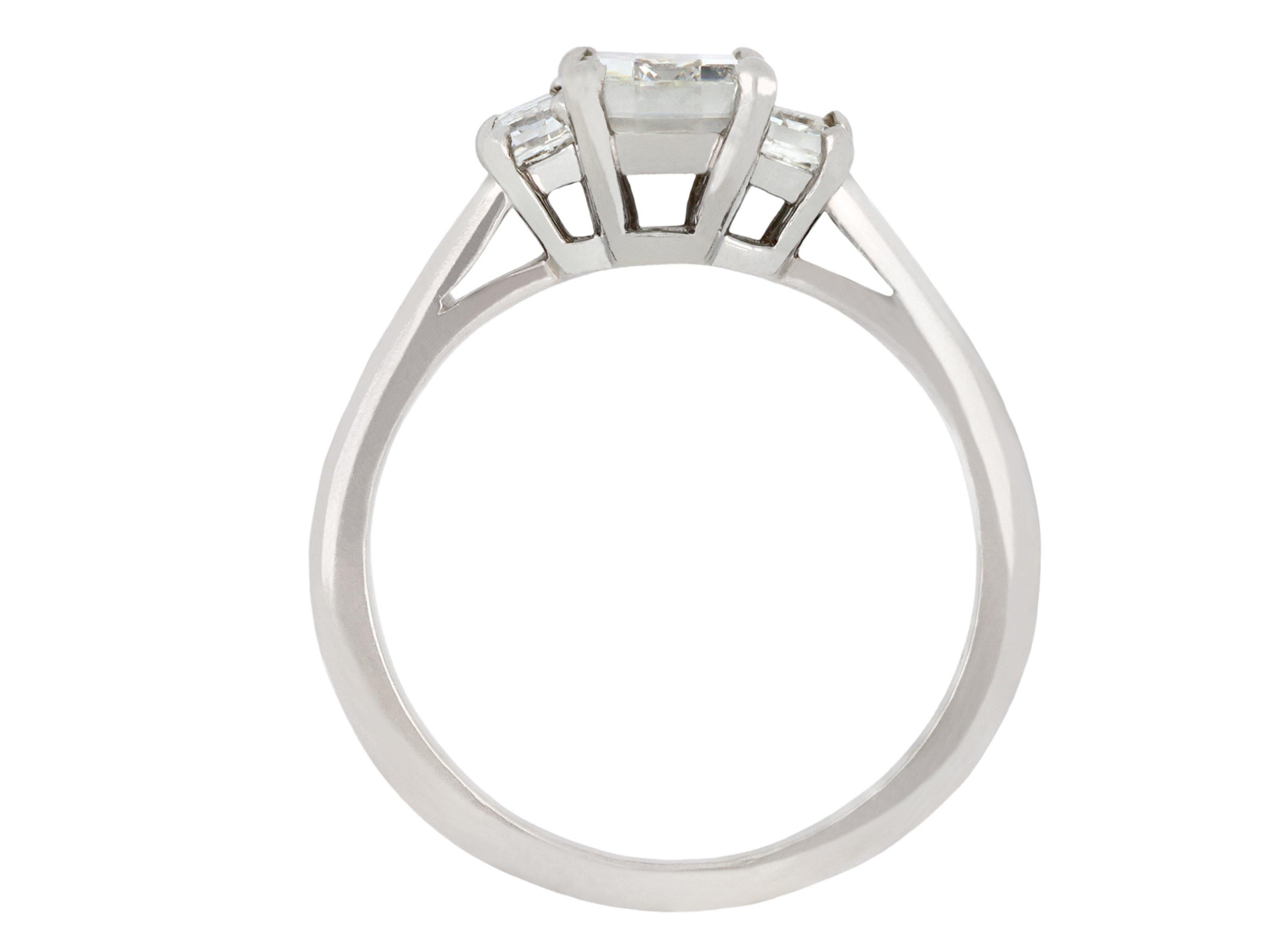 Cartier Diamant Flanke Solitär Ring. In der Mitte befindet sich ein rechteckiger Diamant im Stufenschliff in einer offenen Krallenfassung mit einem ungefähren Gewicht von 0,95 Karat, flankiert von zwei rechteckigen Diamanten im Baguetteschliff in