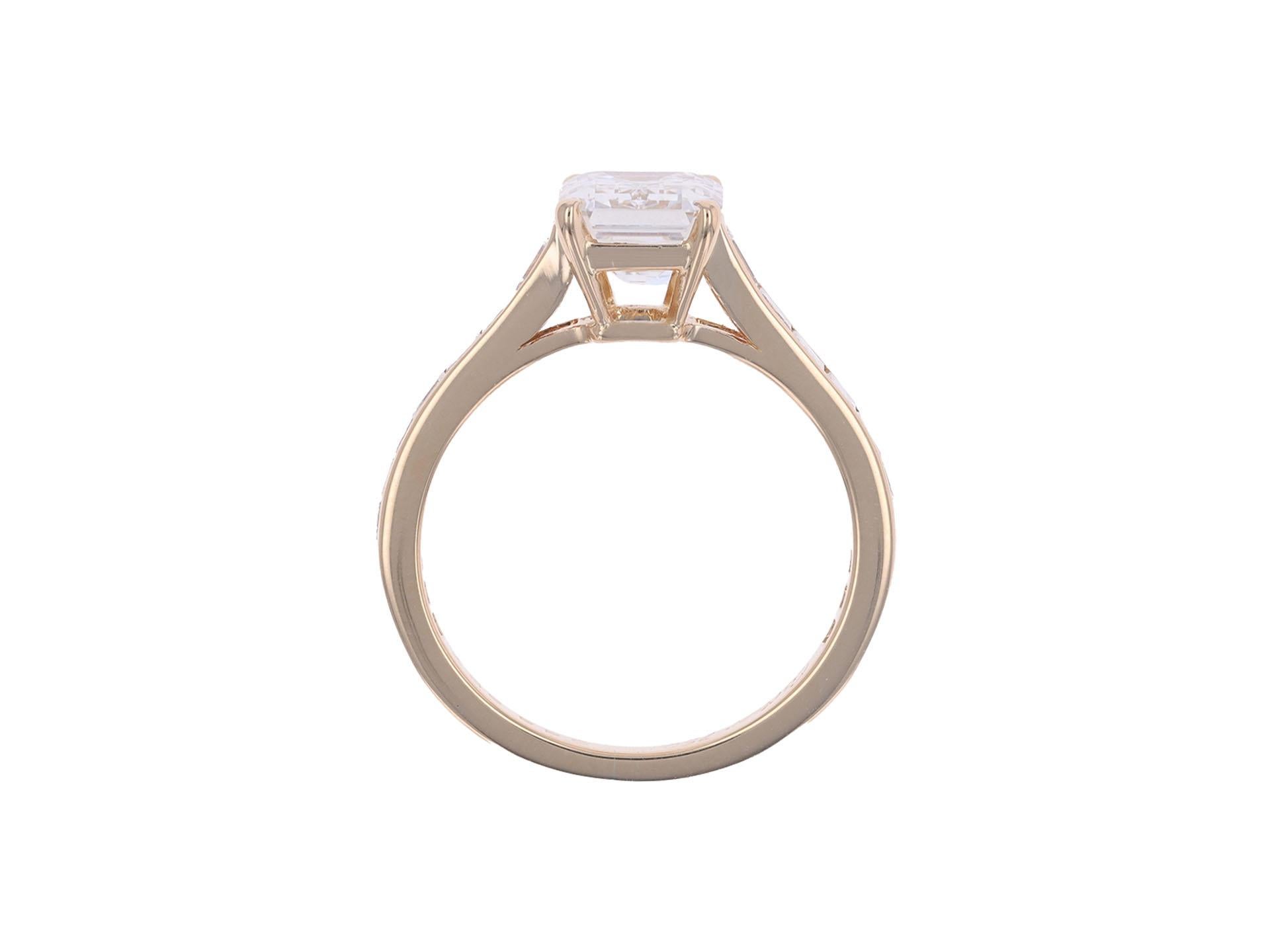 Cartier diamond flanked solitaire ring. Set to centre with an octagonal emerald cut diamond, H colour, VVS2 clarity, with a weight of 2.13 carats, in an open back claw setting, flanked by twenty square step cut diamonds in open back rubover and