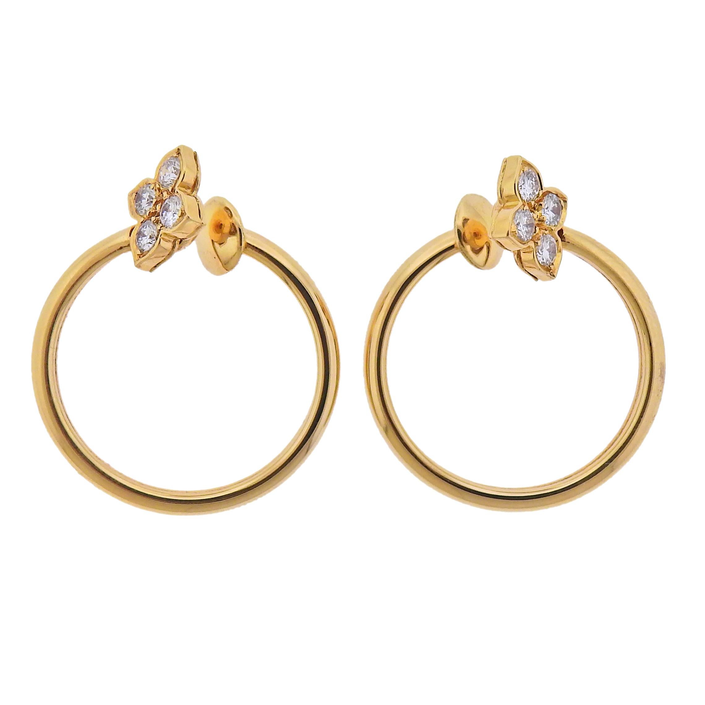 Pair of 18k gold open circle earrings by Cartier, with approx. 0.64ctw in G/VS diamonds. Earrings are 25mm in diameter, diamond flower element - 10mm x 9mm.  Marked: 286879, 750, French mark, Cartier.  Weight - 9 grams. 