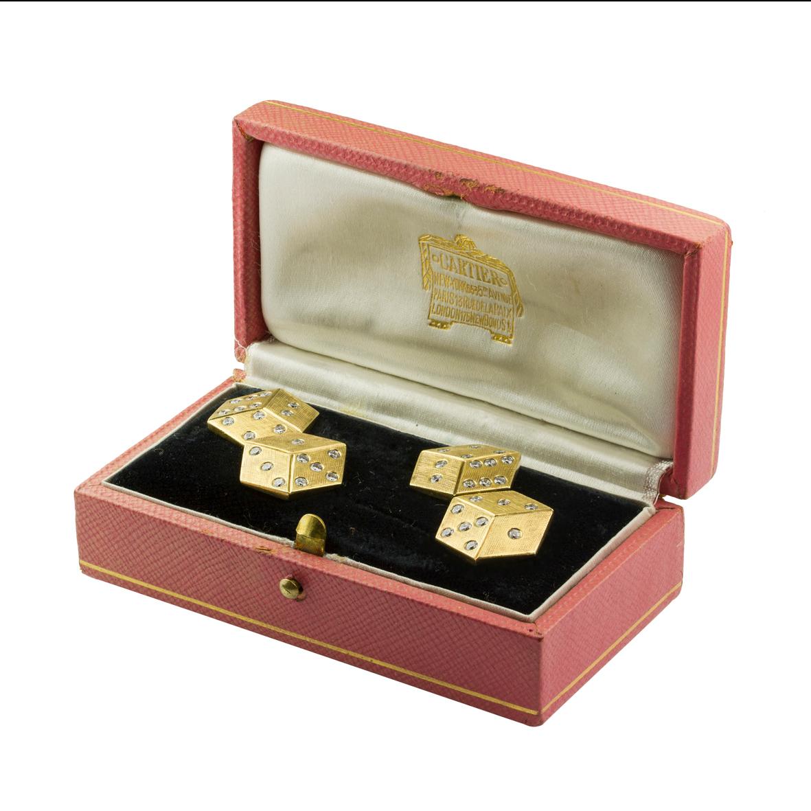 A pair of 1950s Cartier dice cufflinks, each link comprising two three-dimensional cross-etched yellow gold dice, set with round brilliant-cut diamonds, estimated to weigh a total of 0.55 carats, with chain link connections, signed Cartier, gross