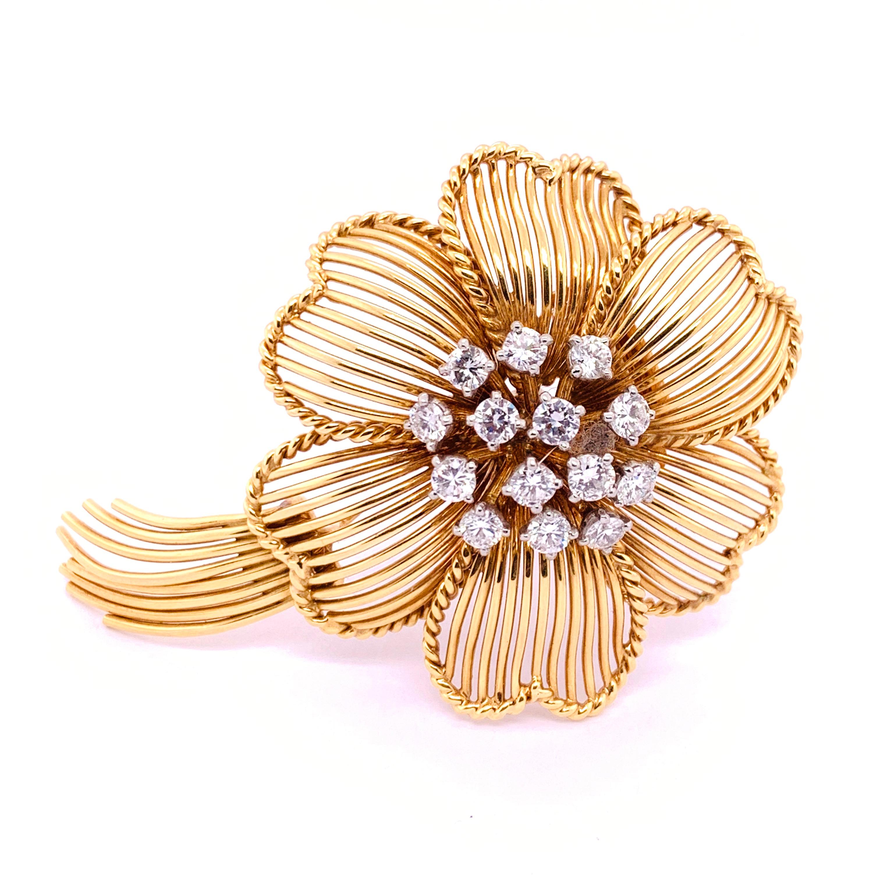A Cartier gold and diamond flower brooch, comprising a cluster of diamonds to the centre with open work gold wire petals and stem. Estimated total diamond weight 2.10cts. Mounted in 18ct gold. Signed Cartier with French marks. Circa 1960.