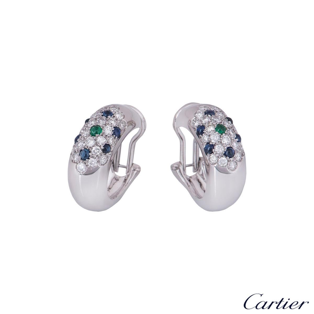 A stunning pair of 18k white gold clip-on earrings by Cartier. Each domed hoop comprises of 22 pave set round brilliant cut diamonds and 6 cabochon cut sapphires, complemented by a single cabochon cut emerald in the centre. The round brilliant cut