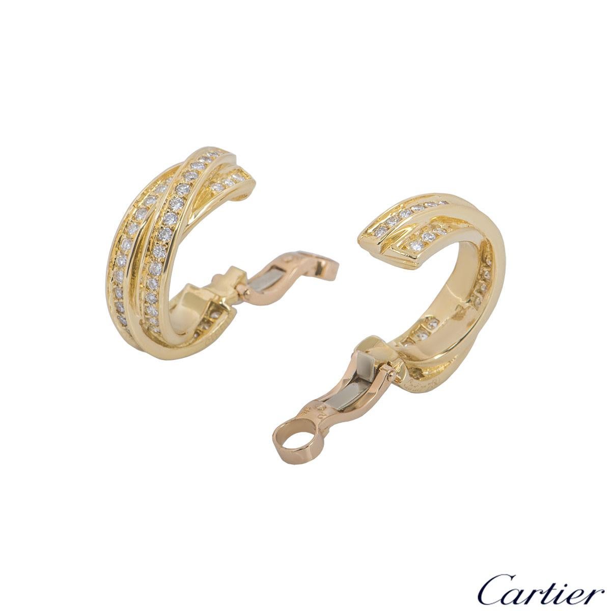 A beautiful pair of 18k yellow gold diamond hoop earrings by Cartier from the Trinity de Cartier collection. The earrings comprise of 3 intertwined yellow gold bands with 90 round brilliant cut diamond set in a pave setting throughout. The earrings