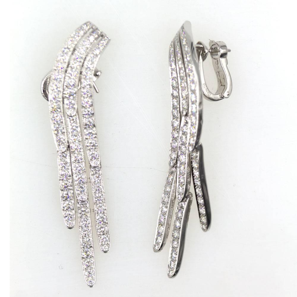These fabulous diamond drop earrings by Cartier are fashioned in platinum. Over 7 carats of high quality round brilliant cut diamonds dangle at different lengths. The earrings measure 2 inches in length. Signed Cartier  PT 950 and numbered RZ4...