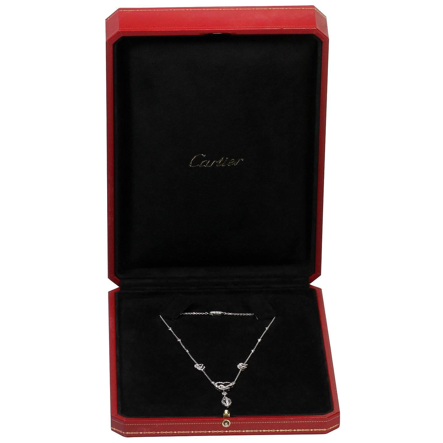 This exquisite Cartier necklace is crafted in 18k white gold and accented with brilliant-cut round diamonds featuring an elegant design of three double hearts, a pendant drop, bezel-set diamond accents, and a sparkling clasp pave set with diamonds