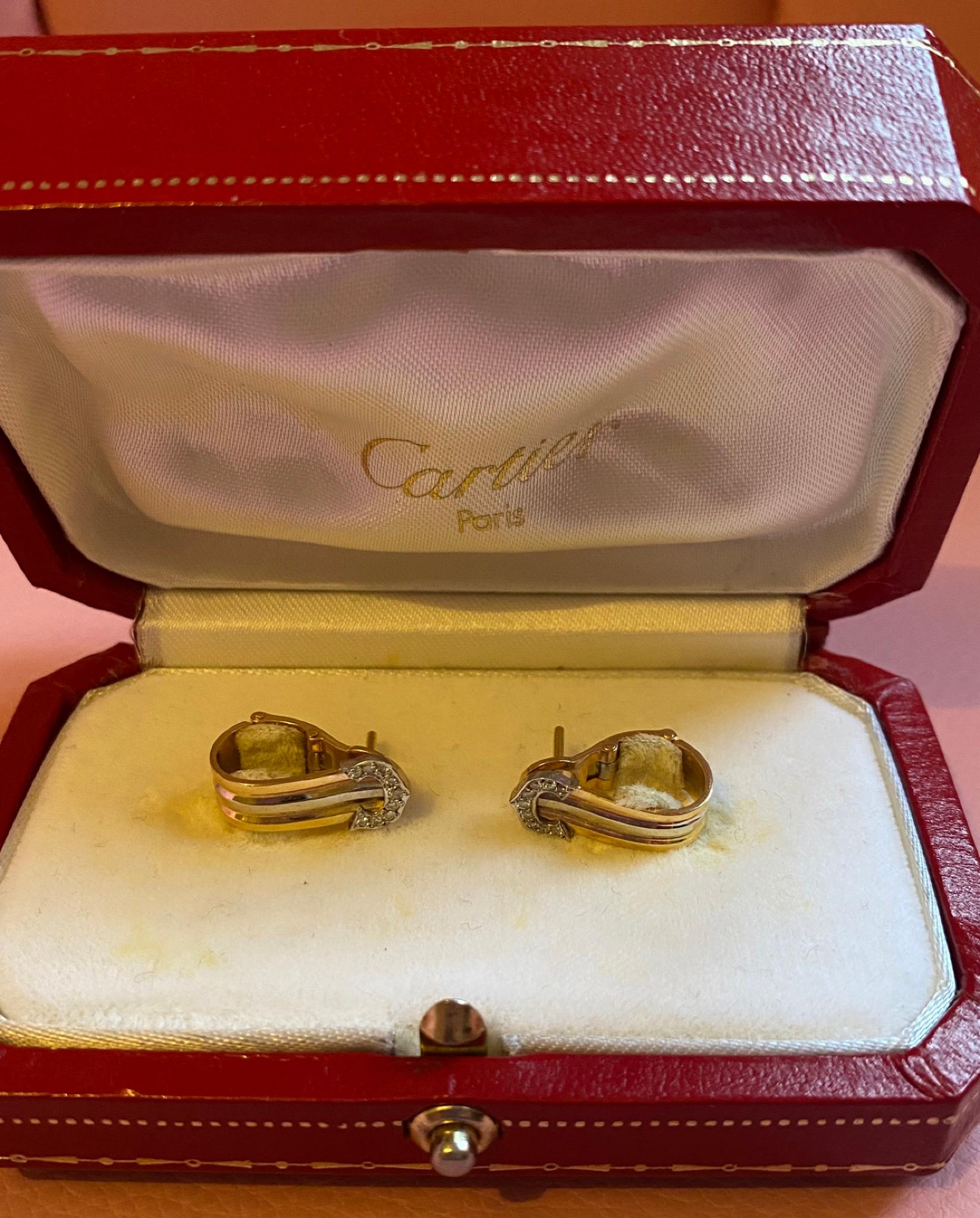 Este elegante par de pendientes Cartier presenta un diseño de tres tonos, elaborado en amarillo de 18 quilates, blanco de 18 quilates y completado con los icónicos extremos en forma de Doble C engastados con diamantes redondos talla brillante.