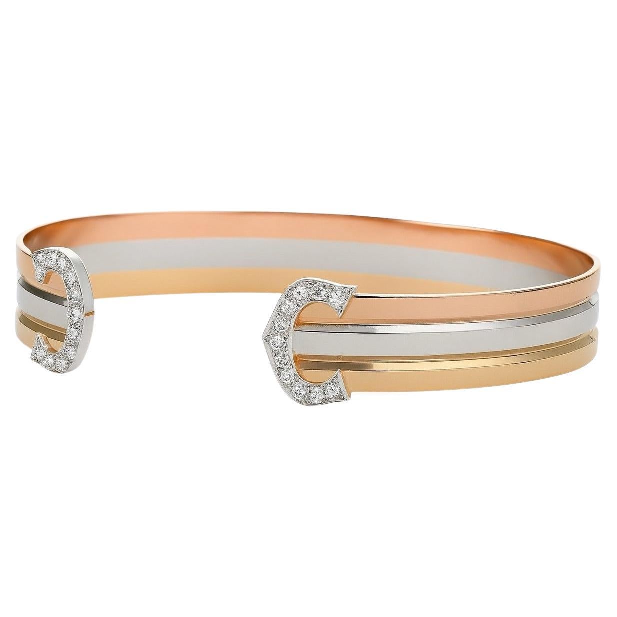 Cartier Double C 18K Tri-Color Gold Diamond Bangle Bracelet

Elegant vintage Cartier Double C bangle bracelet, a discontinued and highly sought-after design.
Expertly crafted in 18K yellow, rose, and white gold, the bracelet weighs 19.8 grams and
