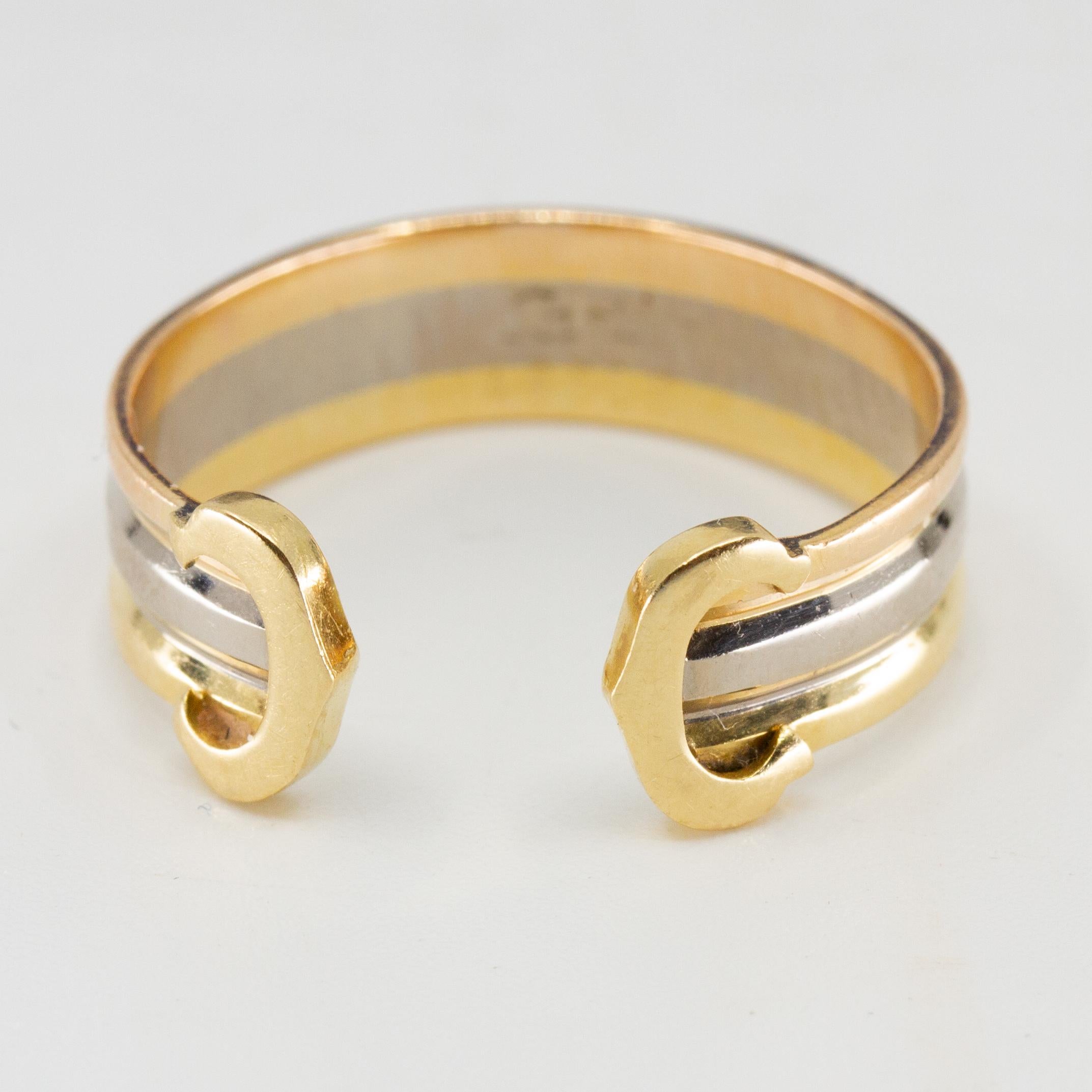 Offered is this lovely authentic band ring by Cartier from the Double C collection. It is crafted from 18k yellow, rose and white gold with a polished finish. The front of the open cuff band has a C on each end with the three color wire band joined