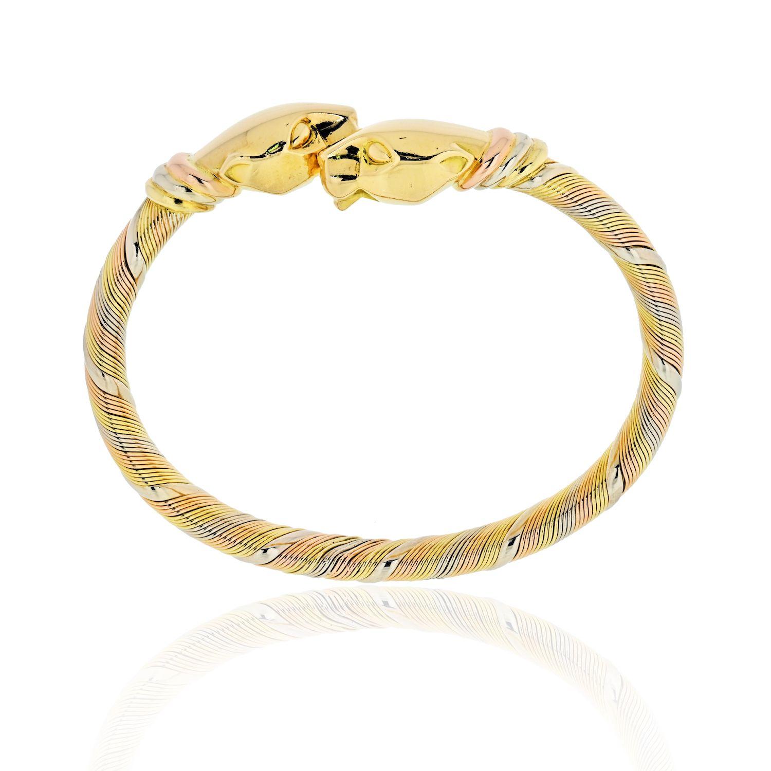 Cartier solid 18k rose, white and yellow gold bracelet with a fine polished finish. This elite piece features a double panther head set in a bypass design. The bracelet is 13mm wide with strips of fine wire fit together in the three gold colors. It