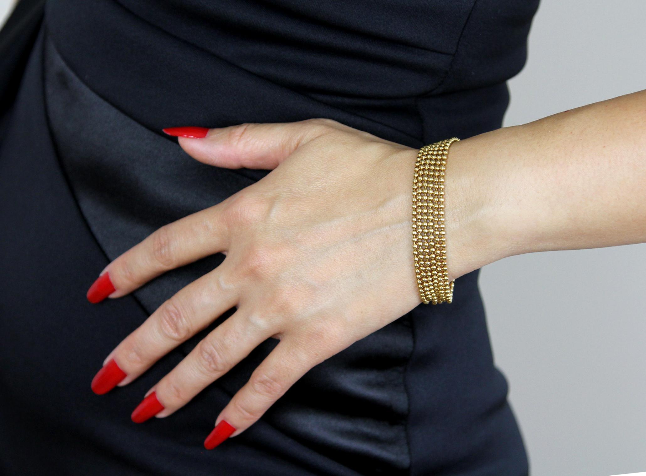 A beautiful Cartier ‘Draperie’ 18 carat gold bracelet designed as six strings of loosely draping golden beads. This elegant, comfortable bracelet is secured with a pair of loop and cabochon gold bead fastenings. 
The bracelet is 173 mm long, width