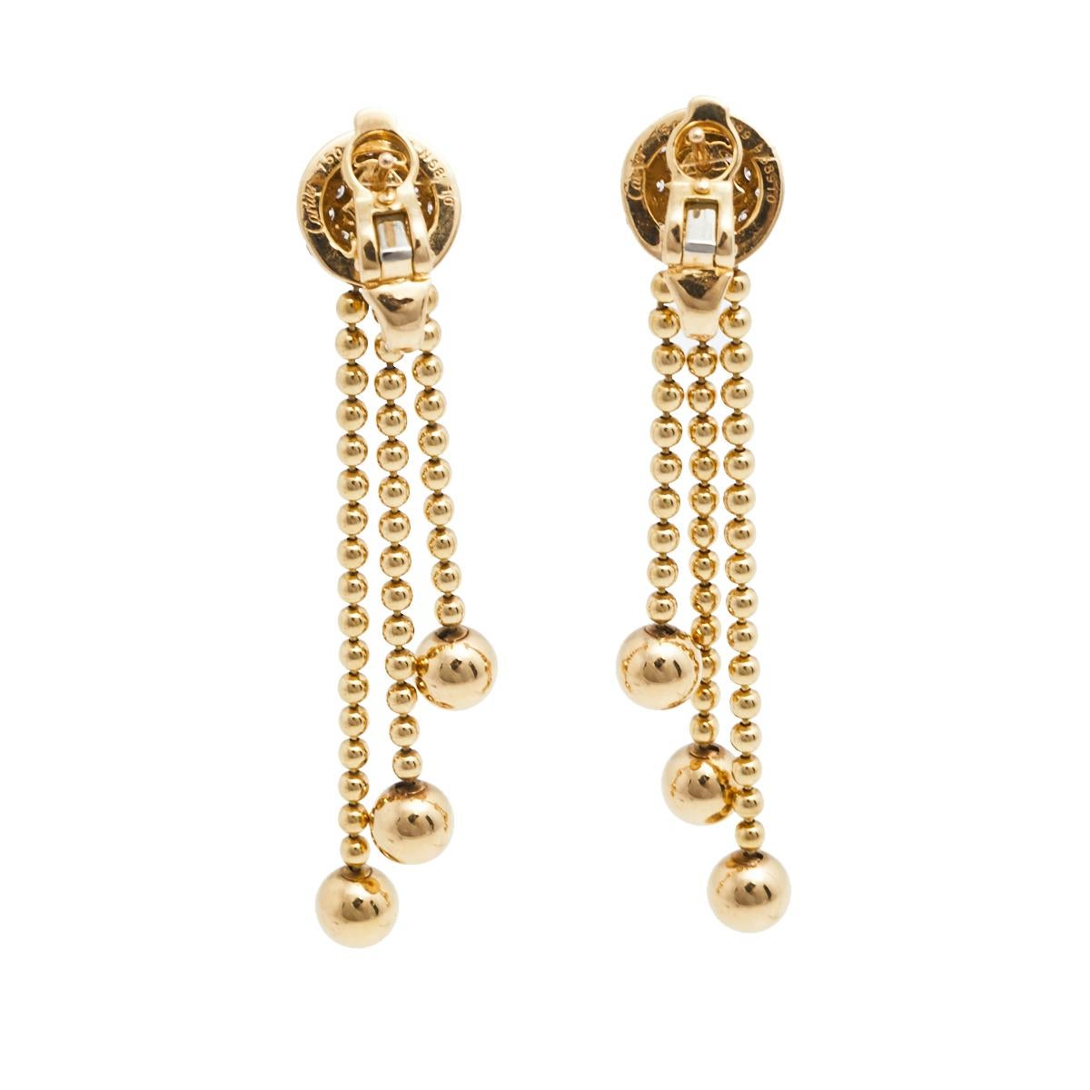 Let's bask and dance in sparkles with Cartier! These incredibly exquisite earrings are made of 18k yellow gold and bring diamond-embellished studs and dangling beaded chains that move with you. At once delicate and bold, these Cartier Draperie