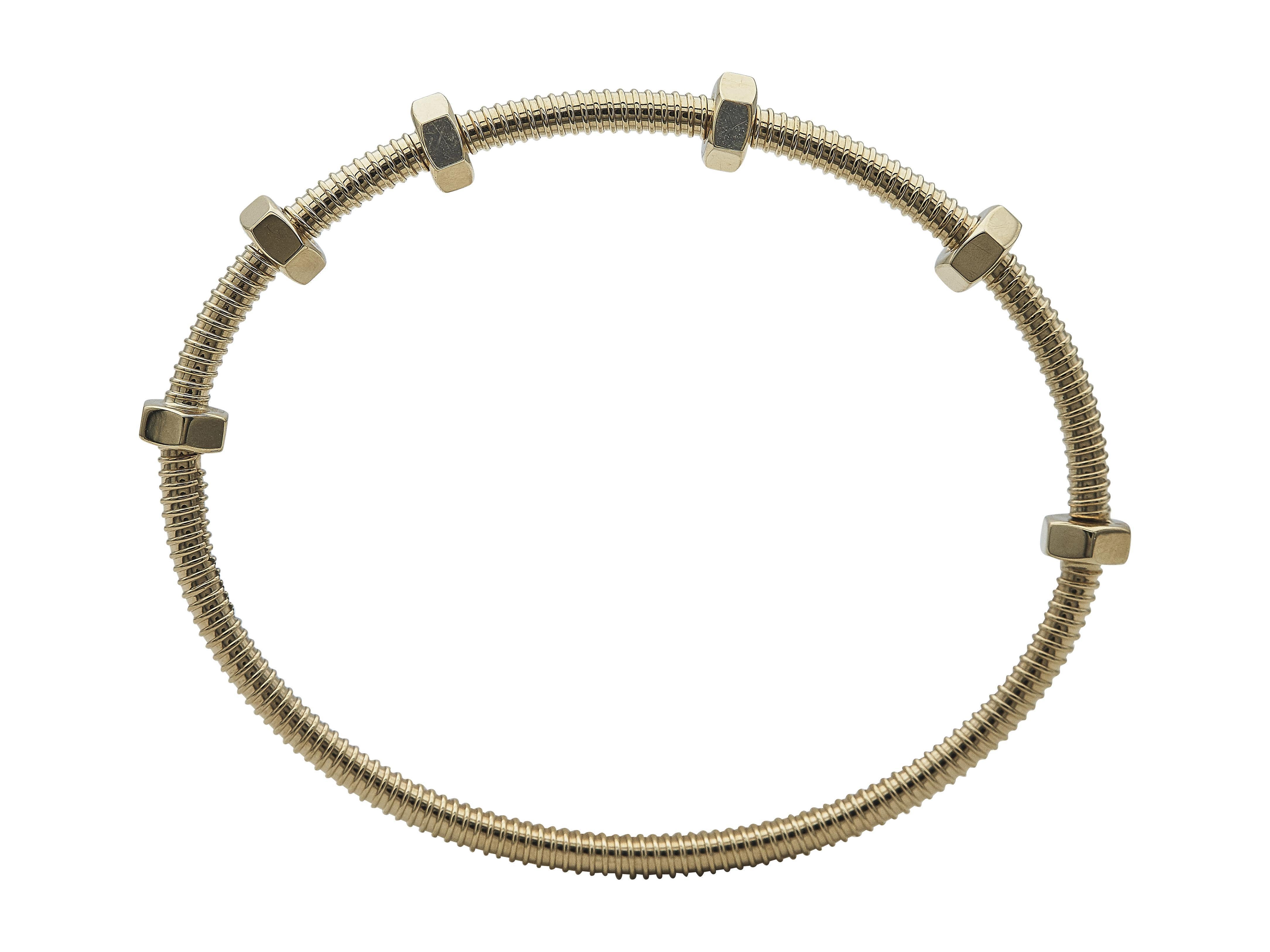 La pulsera: Una pulsera brazalete Ecrou de Cartier. El modelo clásico está diseñado en oro de 18 quilates. Es una talla 19.

Esta pulsera está en excelente estado, con ligeros arañazos superficiales propios del uso normal.

Acompañado