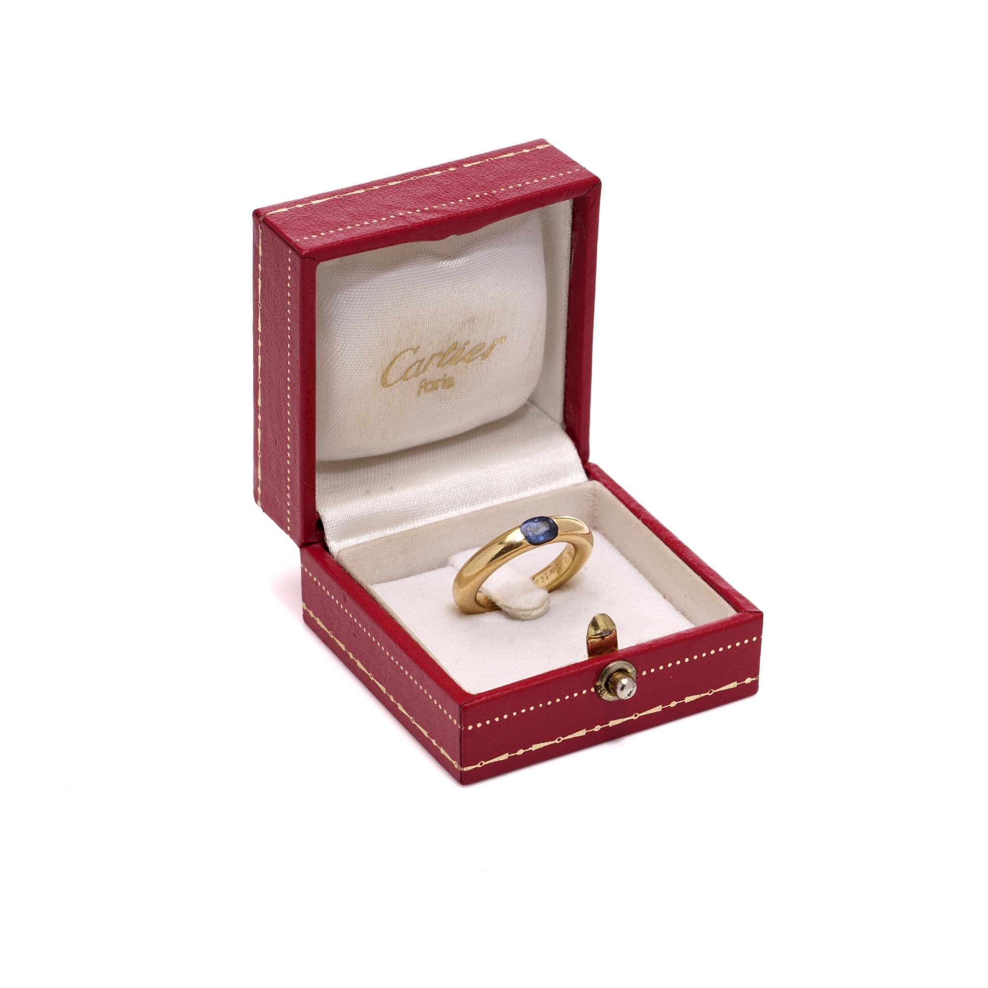 Cartier Ellipse Collection vintage 18kt. yellow gold plain band ring set in demi flush setting, set with an oval 0.40ct. faceted sapphire. 
Designer: Cartier
Made in France, 1992
Fully hallmarked.

Dimensions -
Finger Size (UK) = L US) = 6 (EU) =