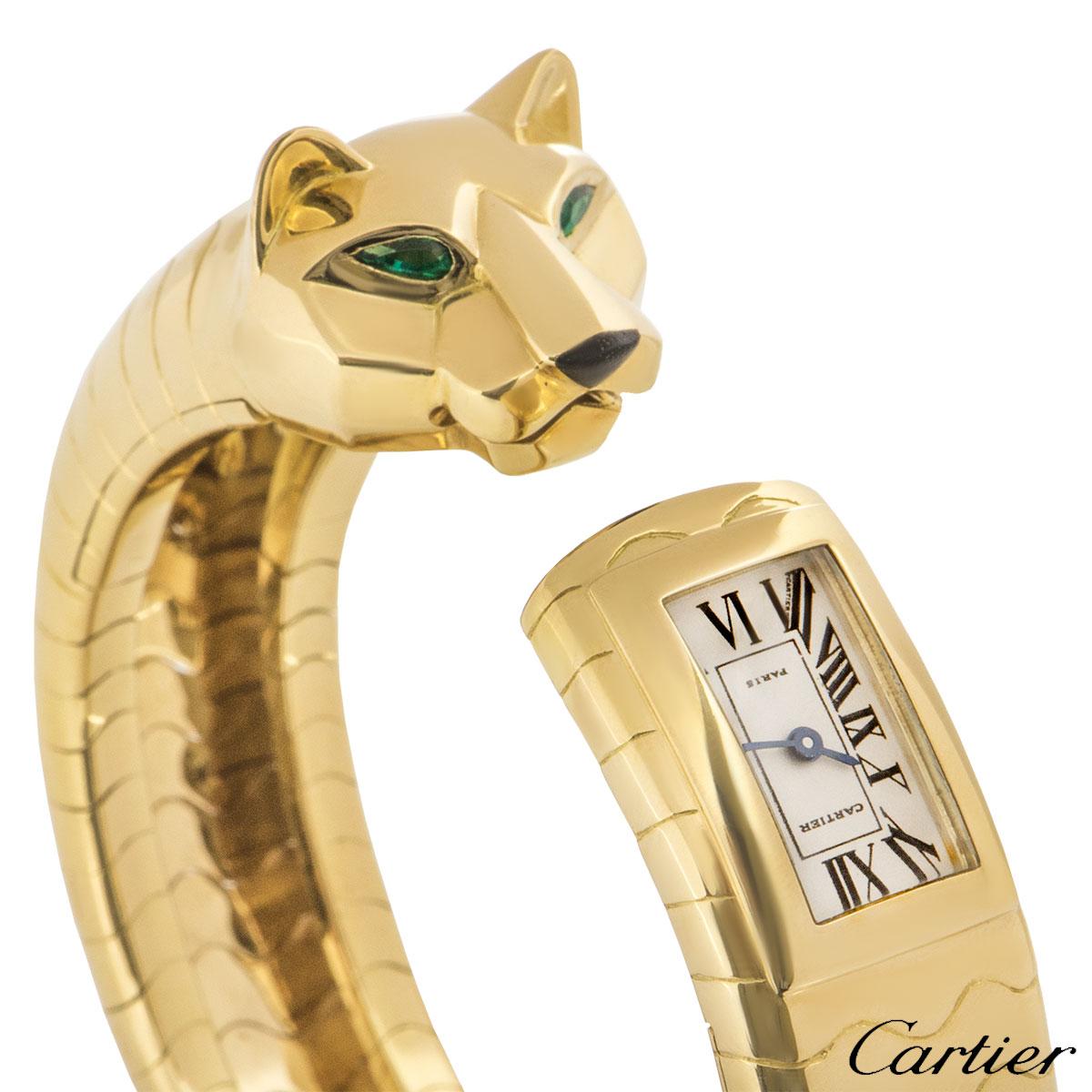 A rare 18k yellow gold cuff bangle watch by Cartier from the Panther Lakard collection. The yellow gold cuff bangle features a panther head set with emerald eyes and an onyx nose on one end and the watch on the other which features a quartz movement