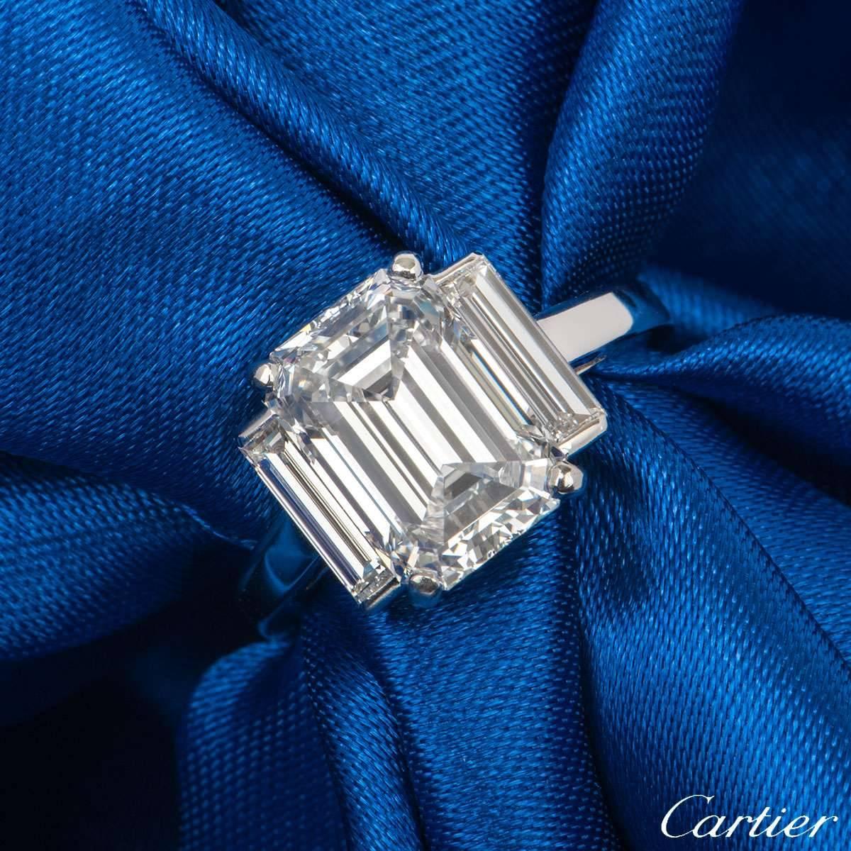 A phenomenal platinum diamond ring by Cartier. The ring is set to the centre with an emerald cut diamond weighing 3.36ct, F colour and VS1 clarity. The diamond is flanked by 2 baguette cut diamonds totalling approximately 0.80ct, well matched in