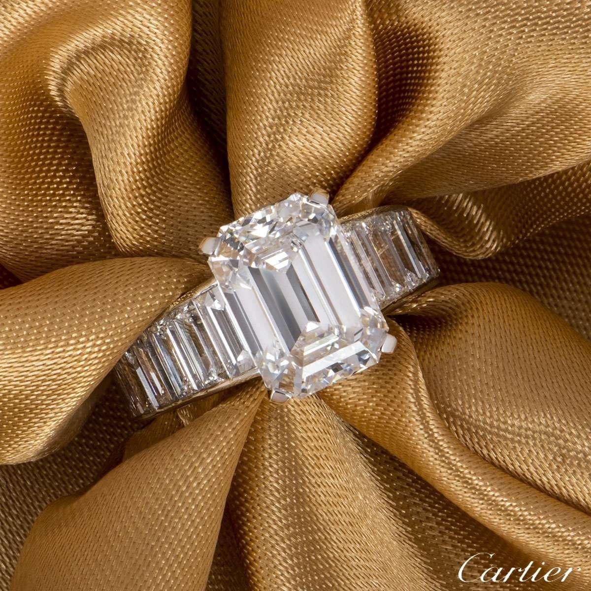 A remarkable emerald cut diamond ring by Cartier. The ring is set to the centre with a 4.12ct diamond, E colour and VVS2 clarity. Complementing the central diamond are 18 baguette cut diamond set shoulders and 2 on the mount with a total weight of