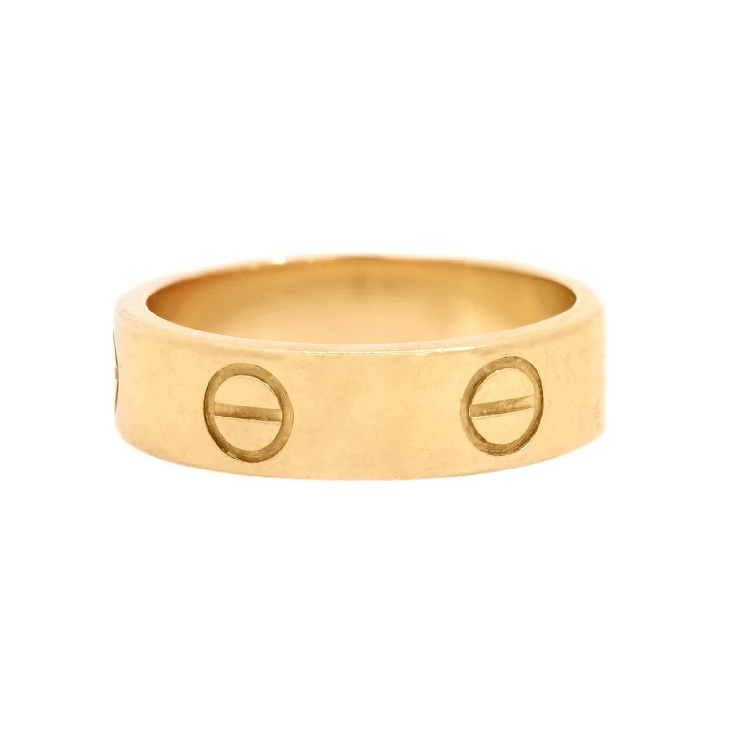 Une fabuleuse bague Estate de la collection iconique LOVE de Cartier ! Réalisée en or jaune 18 carats, cette bague, appelée alliance LOVE, présente un anneau d'or lisse bordé de 6 motifs à vis emblématiques. L'intérieur de la bague porte le cachet