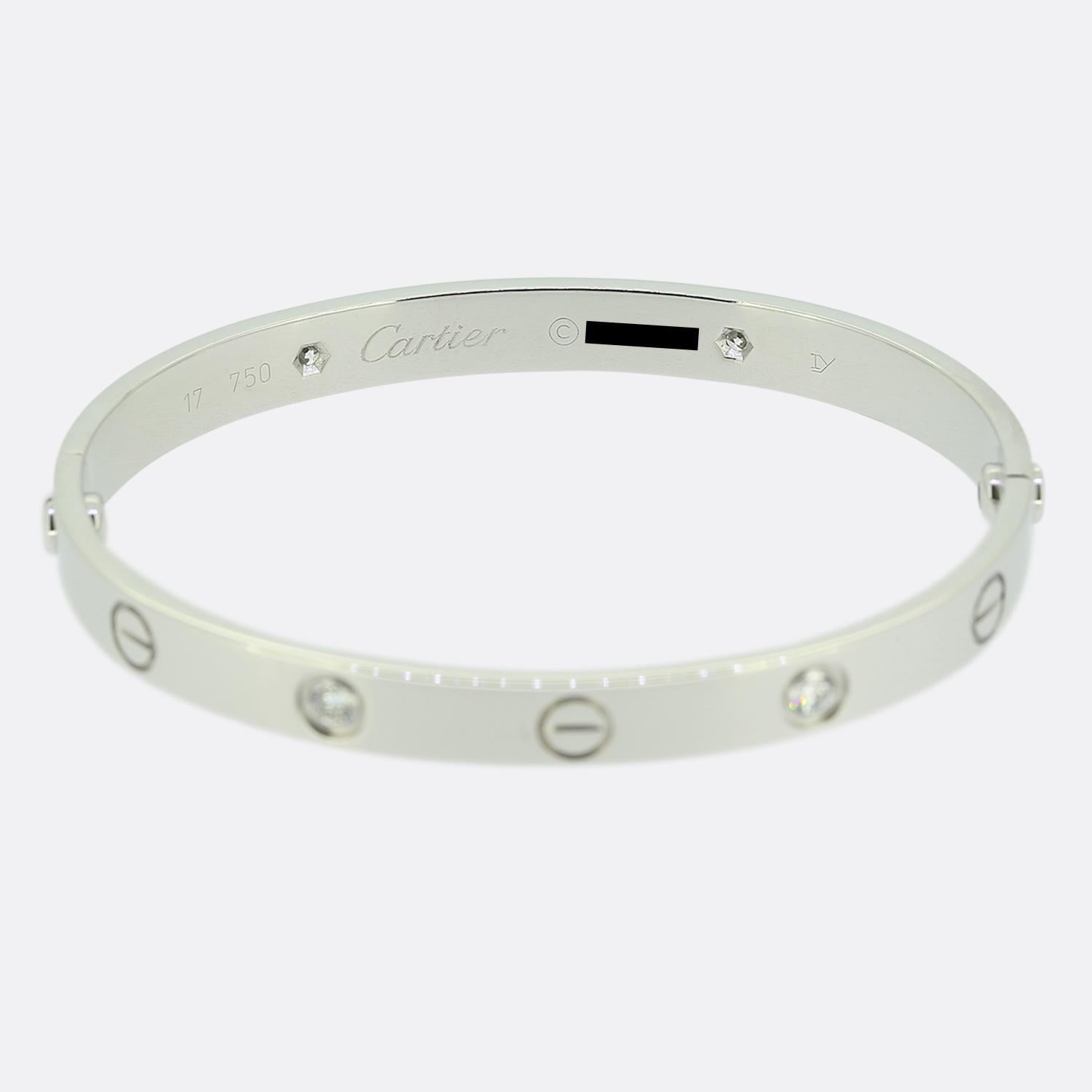 Aquí tenemos un brazalete de oro blanco de 18 ct de la mundialmente conocida casa de joyas de lujo Cartier. Este brazalete forma parte de la colección LOVE y presenta cuatro diamantes redondos de talla brillante junto al icónico motivo del