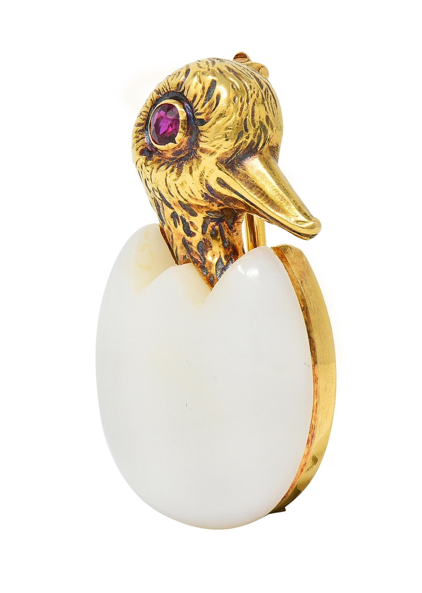 Designed as a stylized gold bird hatching from a carved chalcedony egg
Translucent white in body color - measuring 18.5 x 20.0 mm 
Accented by engraved feather textured head and ruby eye
Round cut and weighing approximately 0.18 carat