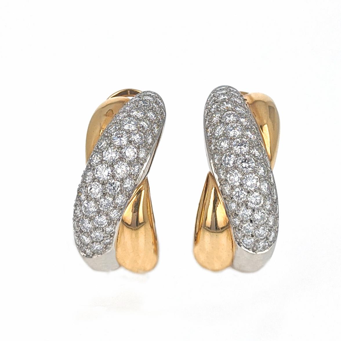 These clip earrings by Cartier France with cross over design feature 118 round brilliant cut diamonds of E/F color and VS clarity with a total approximate weight of 4.5 carats. The earrings are mounted in platinum and 18 karat yellow gold. Each is