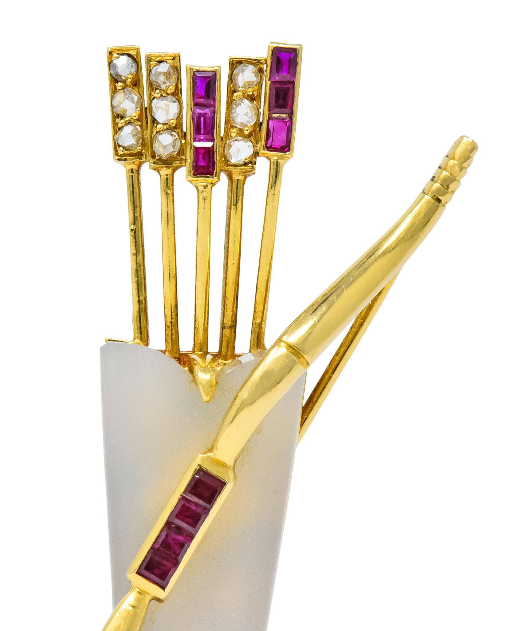 Designed as a bow with a quiver full of arrows

Carved and polished white agate quiver, terminating in a rose cut diamond 

With channel set rose cut diamond and square calibré cut ruby fletchings upon arrows

Bow accented with channel set square