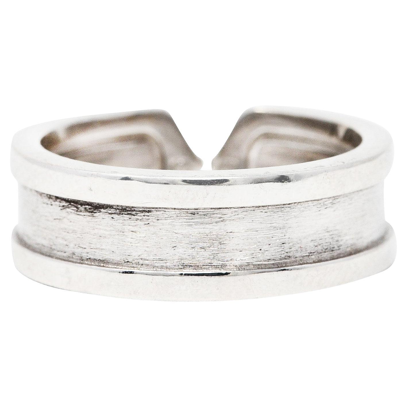 Ring designed as a grooved channel band. Featuring high polished edges and a brushed white gold finish. Completed by two stylized 'C' terminals. Stamped 750 with French and Swiss assay marks for 18 karat gold. Numbered and fully signed Cartier.