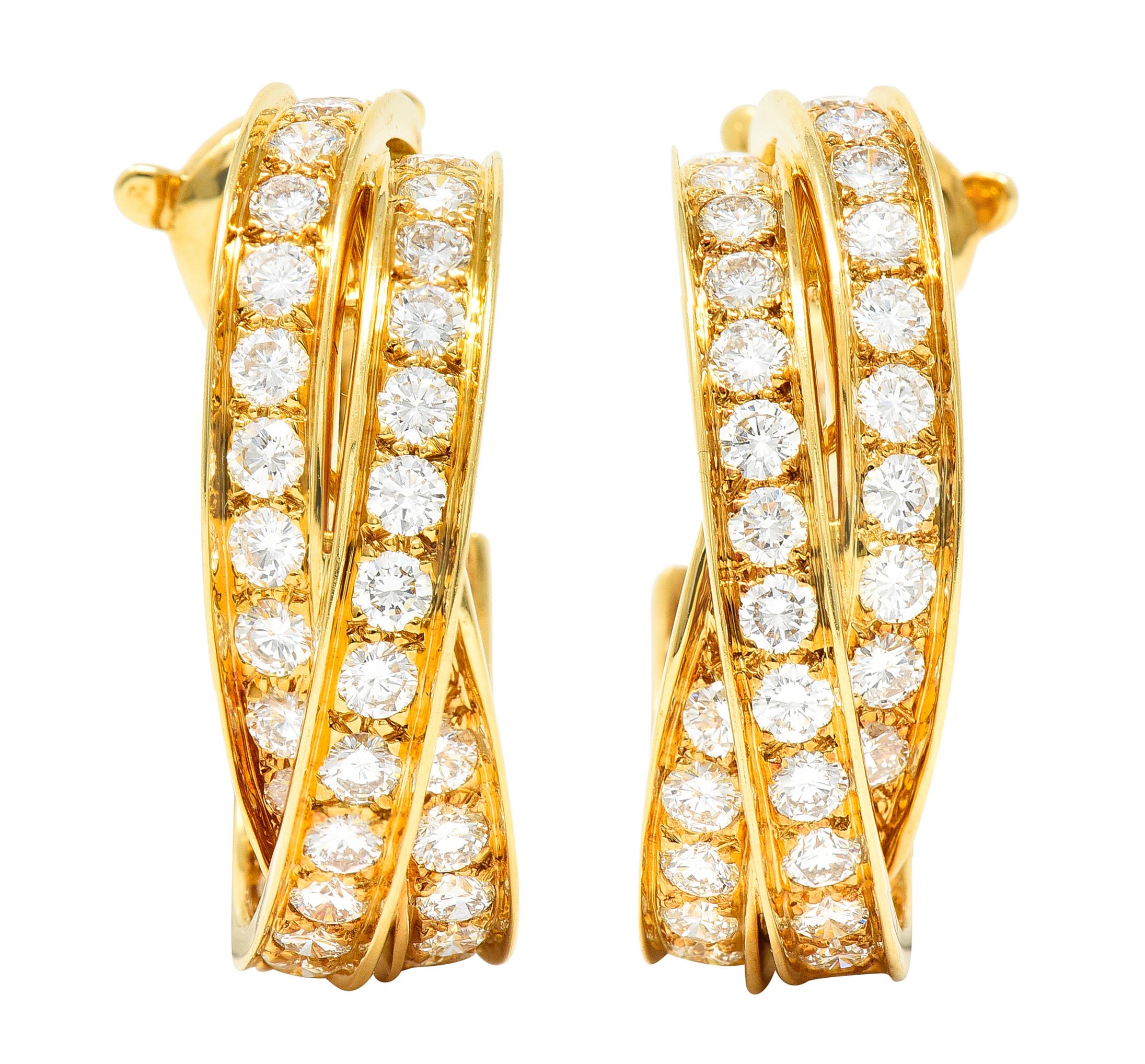 Inside/outside style earrings are designed as three twisting bands with round brilliant cut diamonds. Bead set in recessed channels and weighing approximately 6.15 carats total. F/G in color with VS clarity. Completed by posts with hinged omega