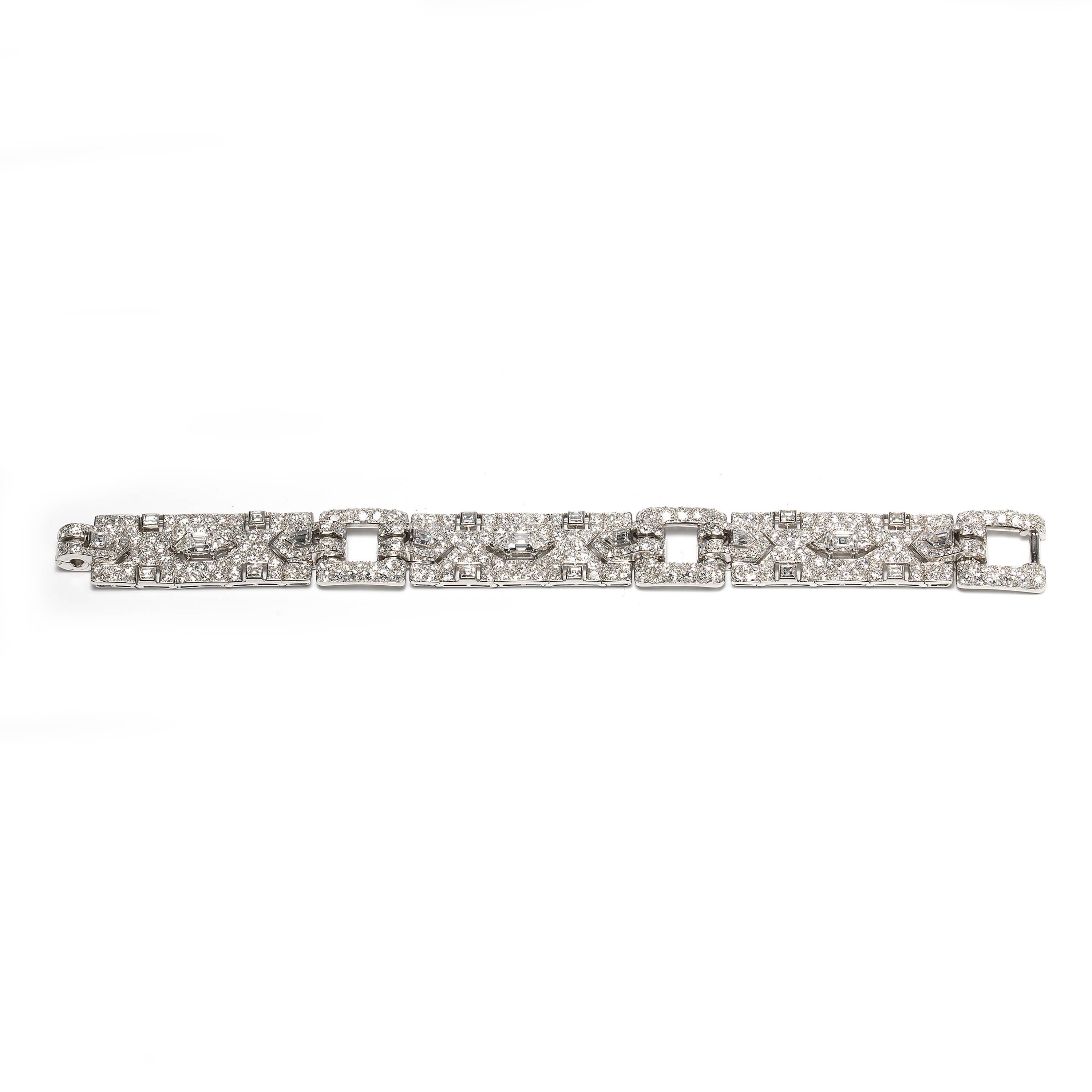 A French, Art Deco, Cartier strap bracelet, comprising three, rectangular, flexible, openwork, pavé set diamond panels, each centre has a trap-cut diamond, in a claw setting, flanked by triangular and fancy-cut diamonds, upon borders of pavé set old