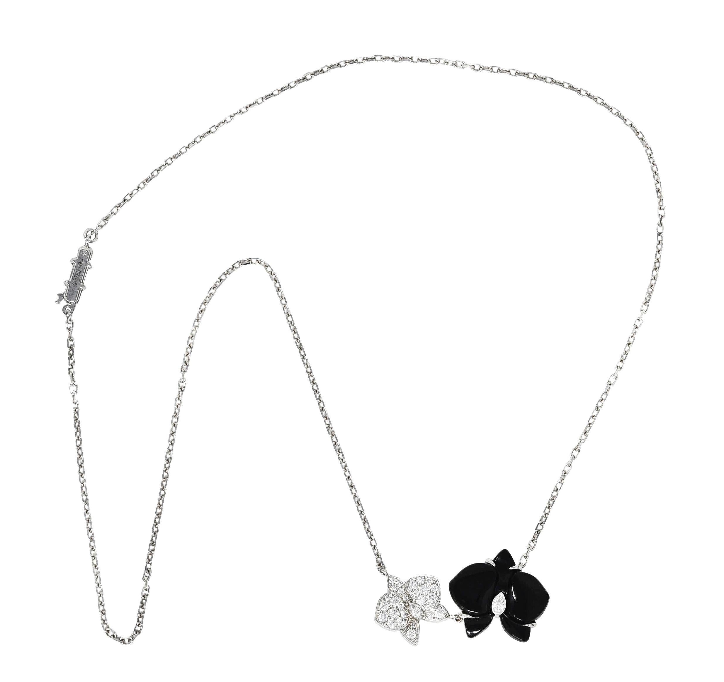 White gold cable chain centers a station comprised of two stylized orchid flowers fixed in place. One is carved from onyx with opaque black color and very good polish - measuring approximately 18.0 x 16.0 mm. Other is platinum with undulating petals