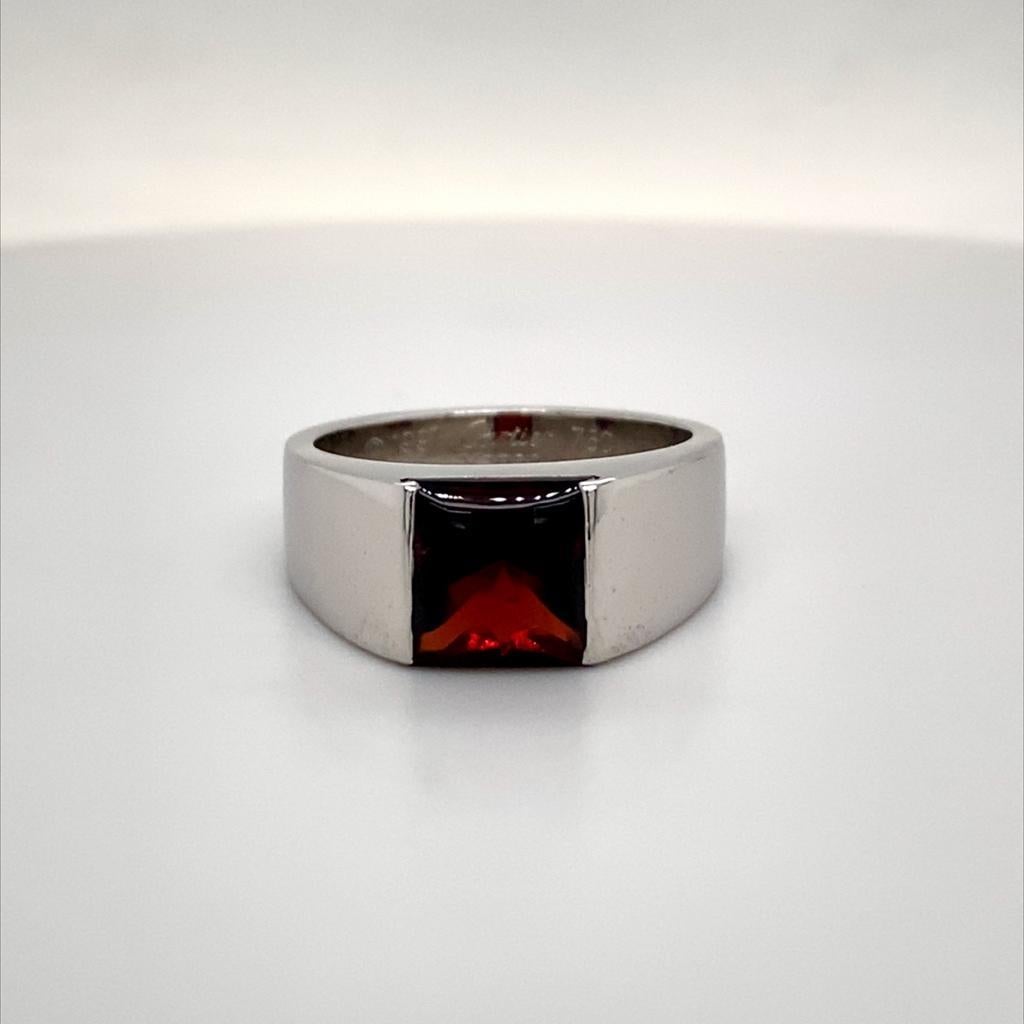 A vintage Cartier garnet Tank ring in 18 karat white gold, circa 1997.

This Iconic Cartier Tank ring by is designed as an 18 karat white gold half rounded band with a square shaped deep red hued garnet in a simple clean open tension setting.

When