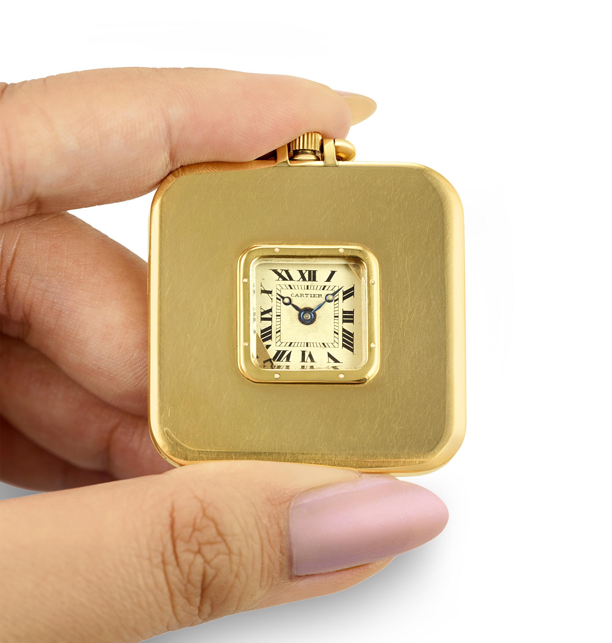 This Art Deco pocket watch was crafted by the famed Cartier. Housed in an 18K gold case, the square-faced timepiece boasts a sleek design. The watch's face, revealed by pressing the knob at its apex, tells the time with black Roman numerals and