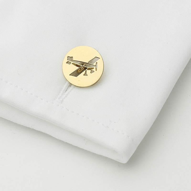 A pair of Cartier gold plane cufflinks, circular gold discs with a cut-out design, one depicting the front view of a biplane, and one depicting an angled side view, with a gold bar connection, mounted in 18ct yellow gold, signed and numbered. Circa