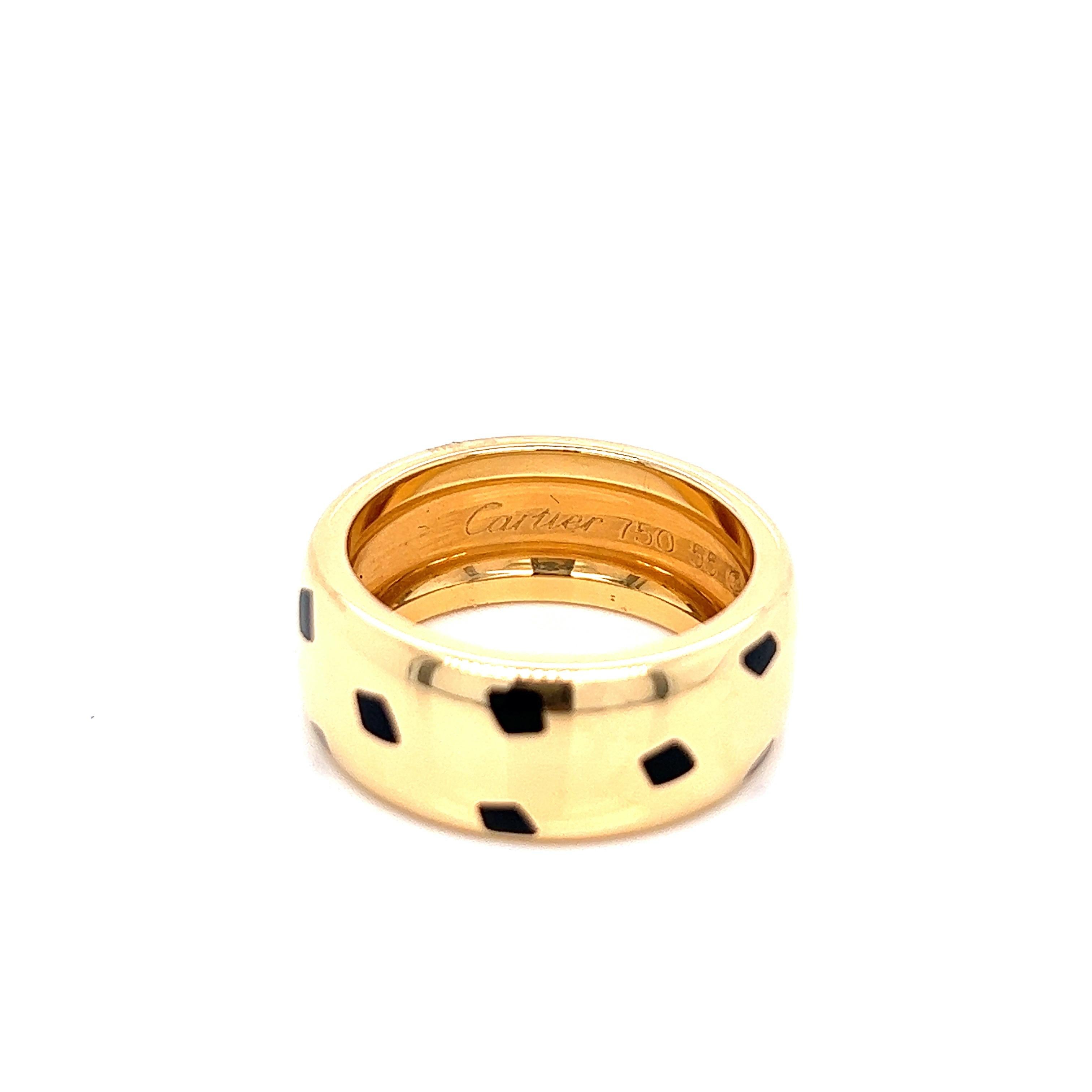 Cartier 18 karat yellow gold ring with spots of black onyx. Serial no. 70675A. Marked: Cartier / 750 / 55 / 70675A. Total weight: 14.7 grams. Width of band: approximately 9 mm. Size 7.5. 