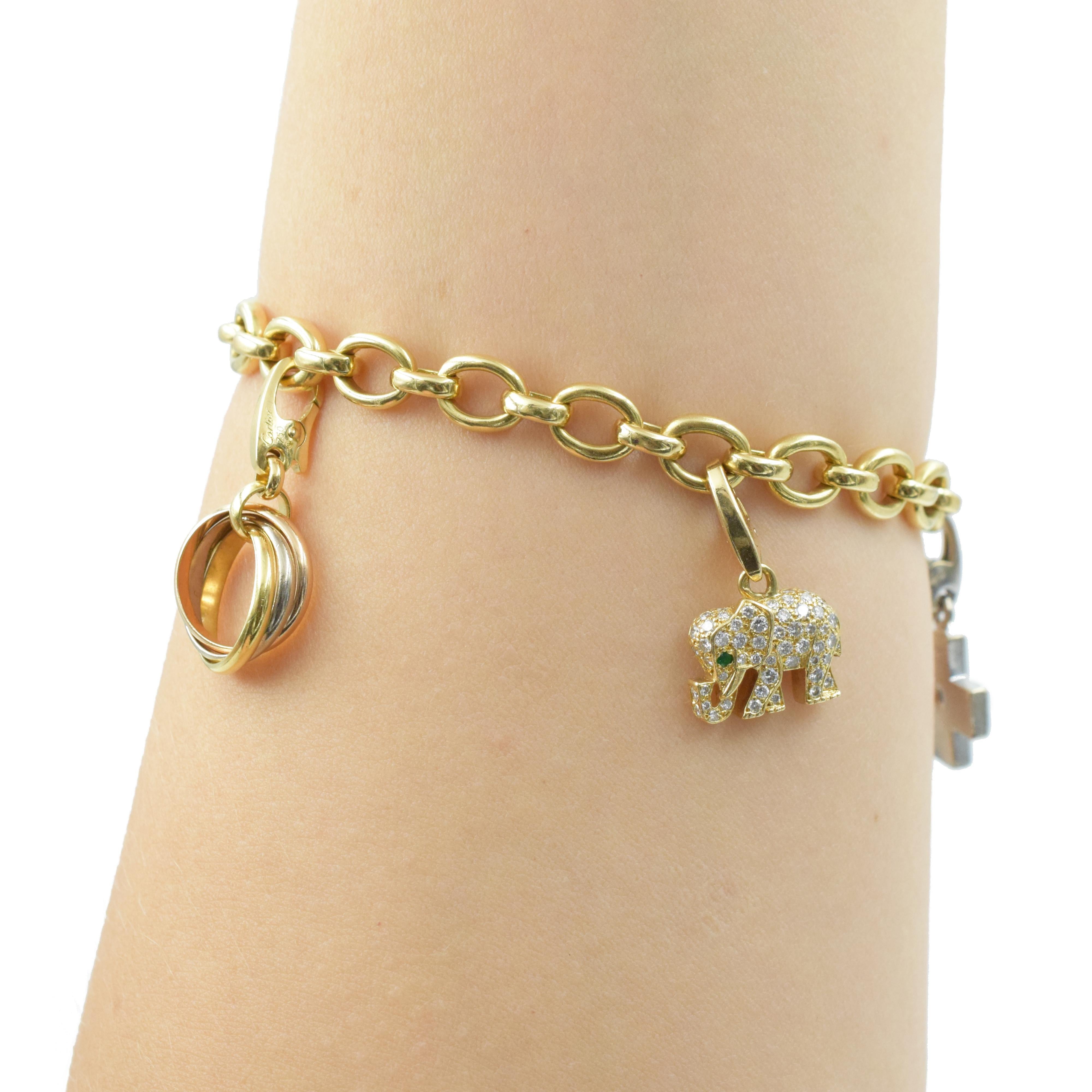 Cartier charm bracelet in 18k yellow gold. This beautiful oval link chain bracelet is 6.5mm wide, signed Cartier, 750, 1995, makers marks and serial number xxxxxx. Accented by five Cartier detatchable charms:1) 18k yellow, white and rose gold
