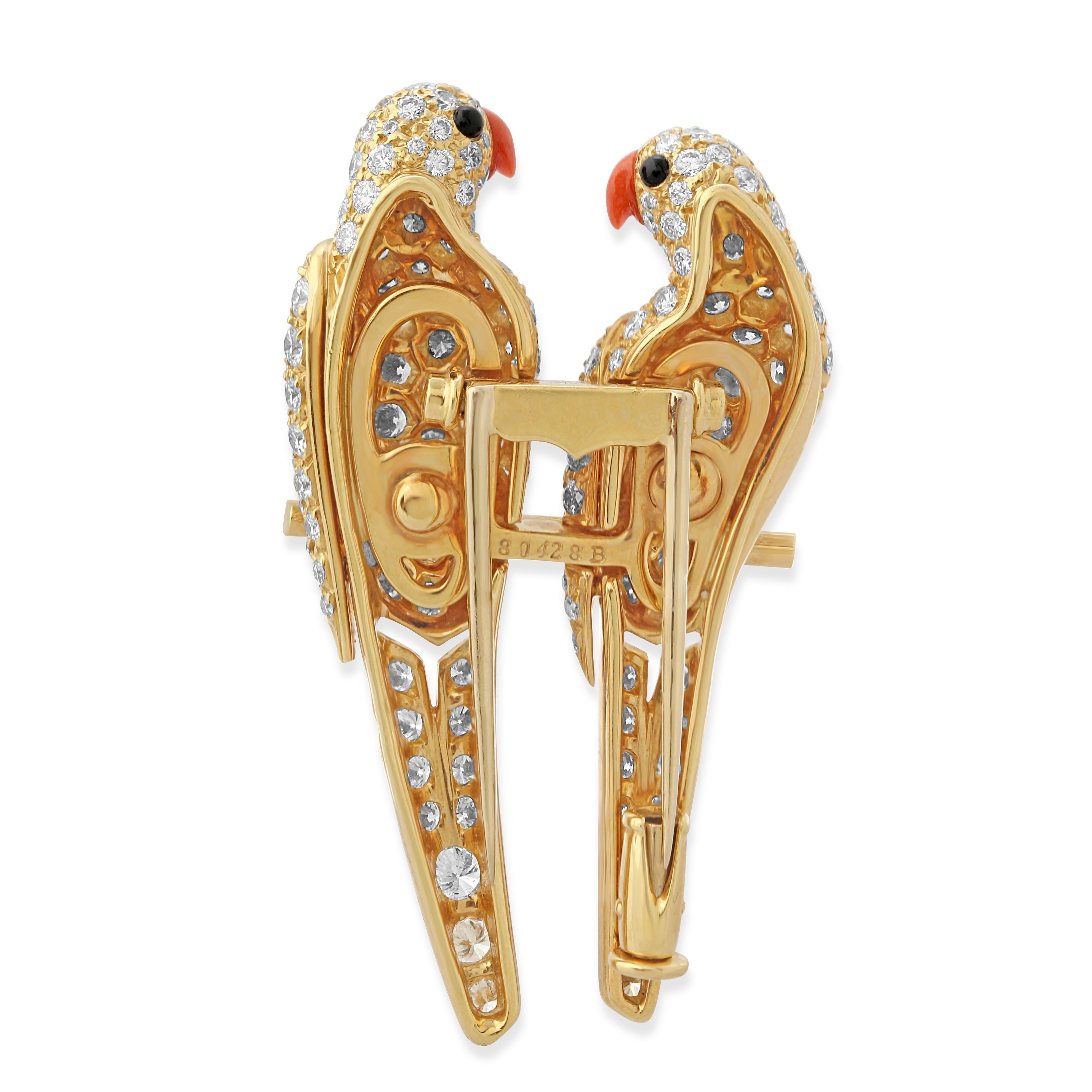 An 18k gold and diamond brooch by Cartier. Stylised as a pair of lovebirds perching on a branch with coral beaks and onyx eyes. Weight = 12.60g.