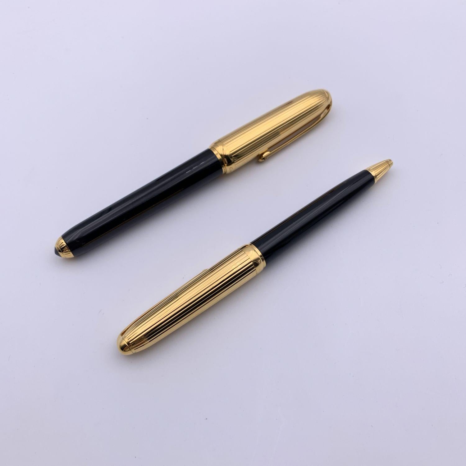 Elegant 'Louis Cartier' set of pens which includes a fountain pen and a ballpoint pen. Black lacquered barrel and gold-plated ribbed cap. 18K yellow gold nib with engraved CC - Cartier logo (18k mark on the nib). The pen is numbered 034917. Total