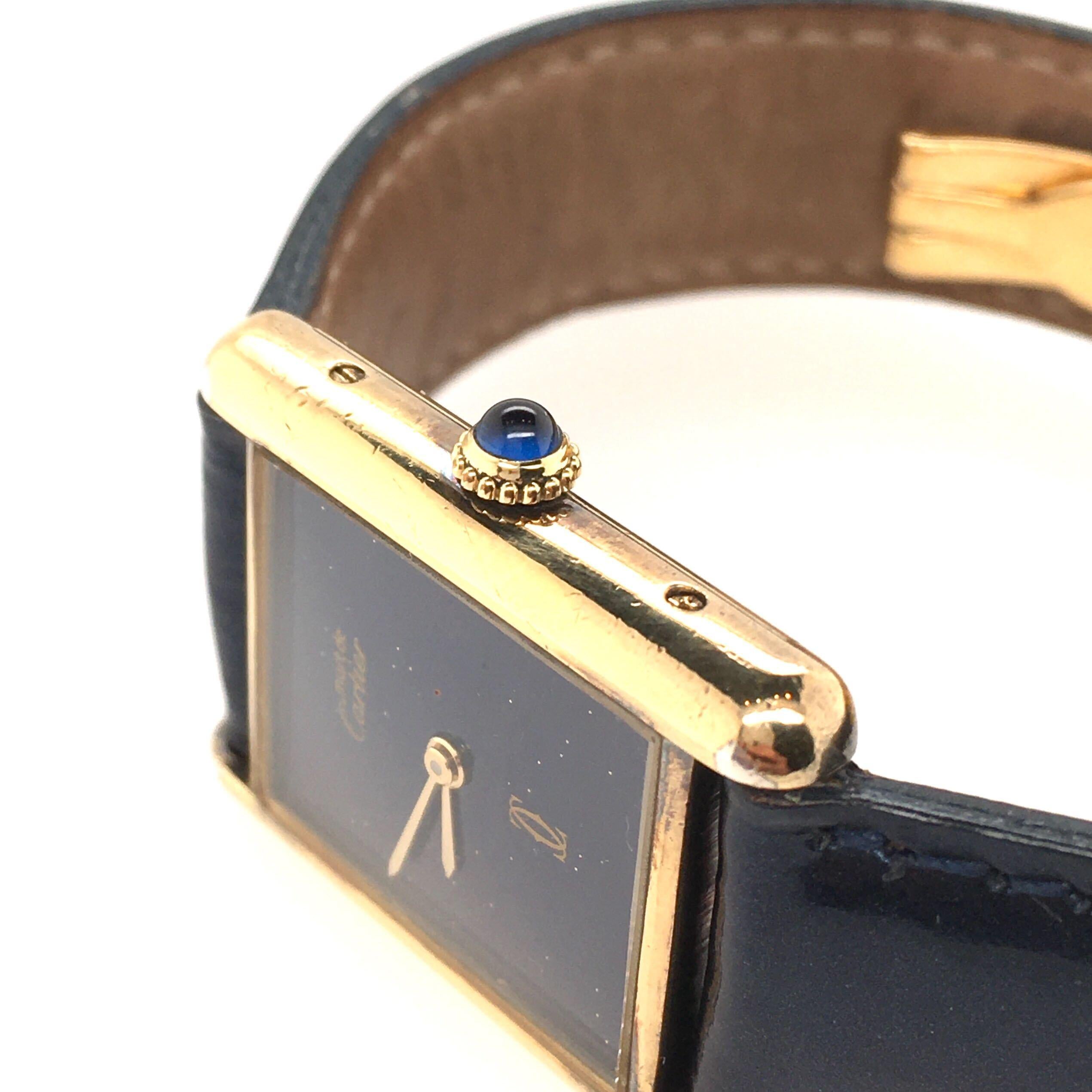 A gold plated over sterling silver and lapis lazuli Tank watch. Cartier, Paris.  Circa 1960. 25 x 22mm. Of mechanical movement, rectangular lapis lazuli dial,with cabochon sapphire crown, joined by a pearled dark blue leather band with deployant