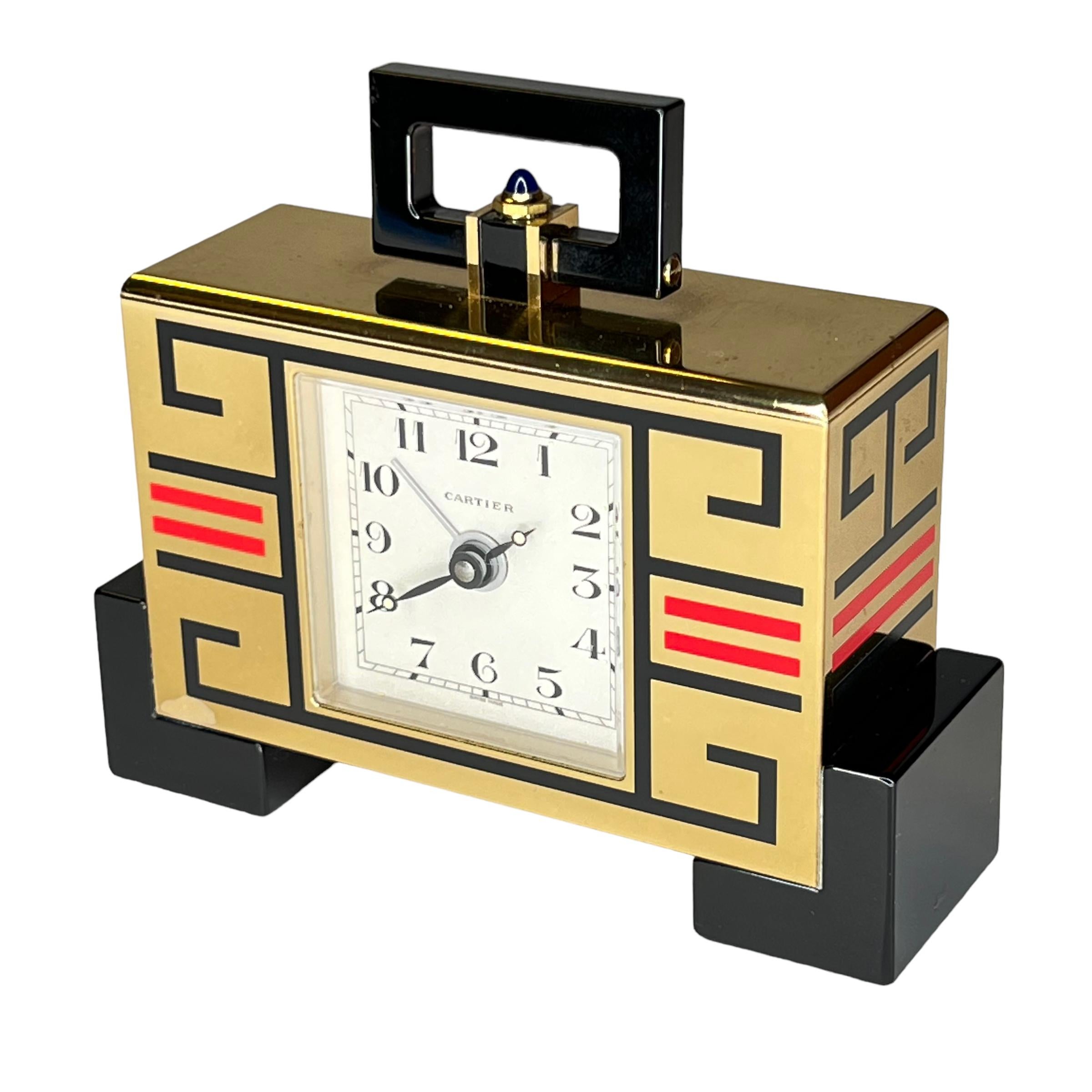Our gold-plated travel clock from Cartier dates from circa 1990 and features fine enamel designs and a sapphire button at top.