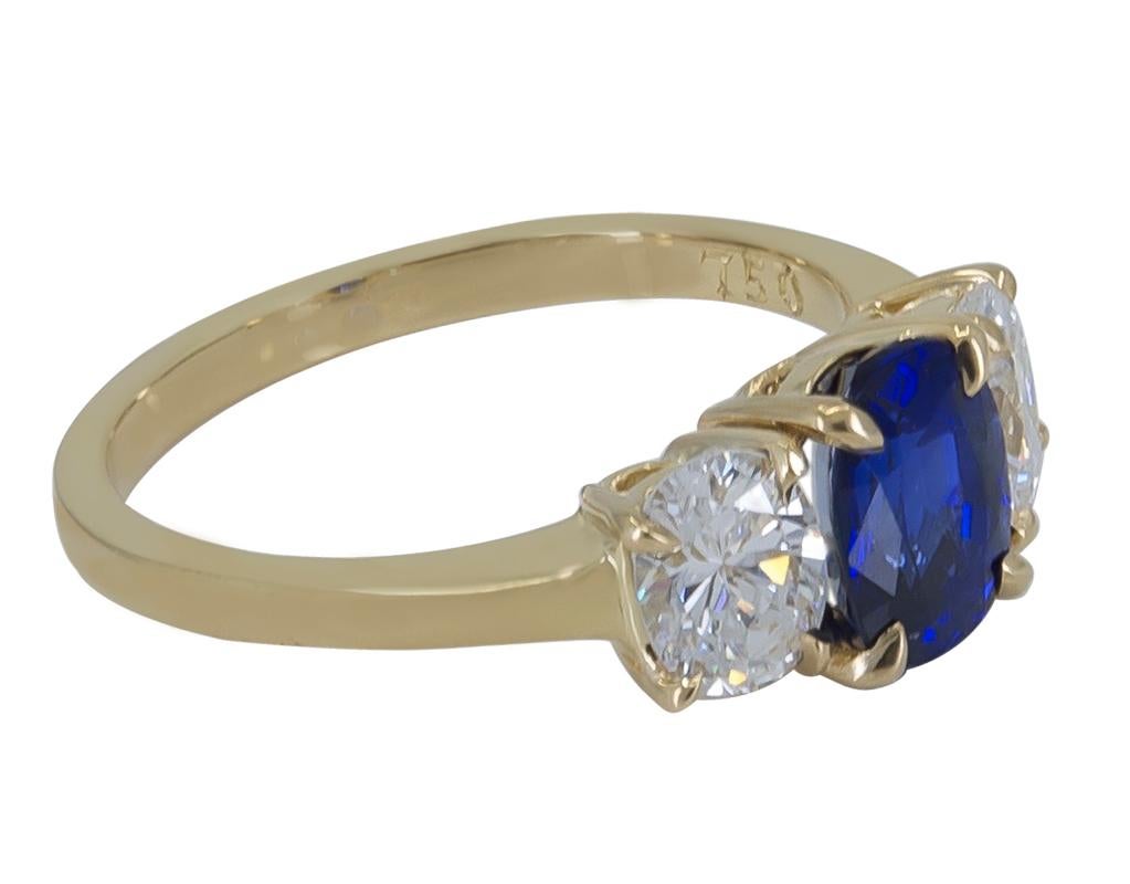 Exceptional handmade Cartier Sapphire and Diamond 18K Yellow Gold Ring.  The exquisite Oval Blue Sapphire is 1.71 carats, accompanied by a GIA (Gemological Institute of America) report.  It is accentuated by two matched Oval Cut Diamonds that weigh