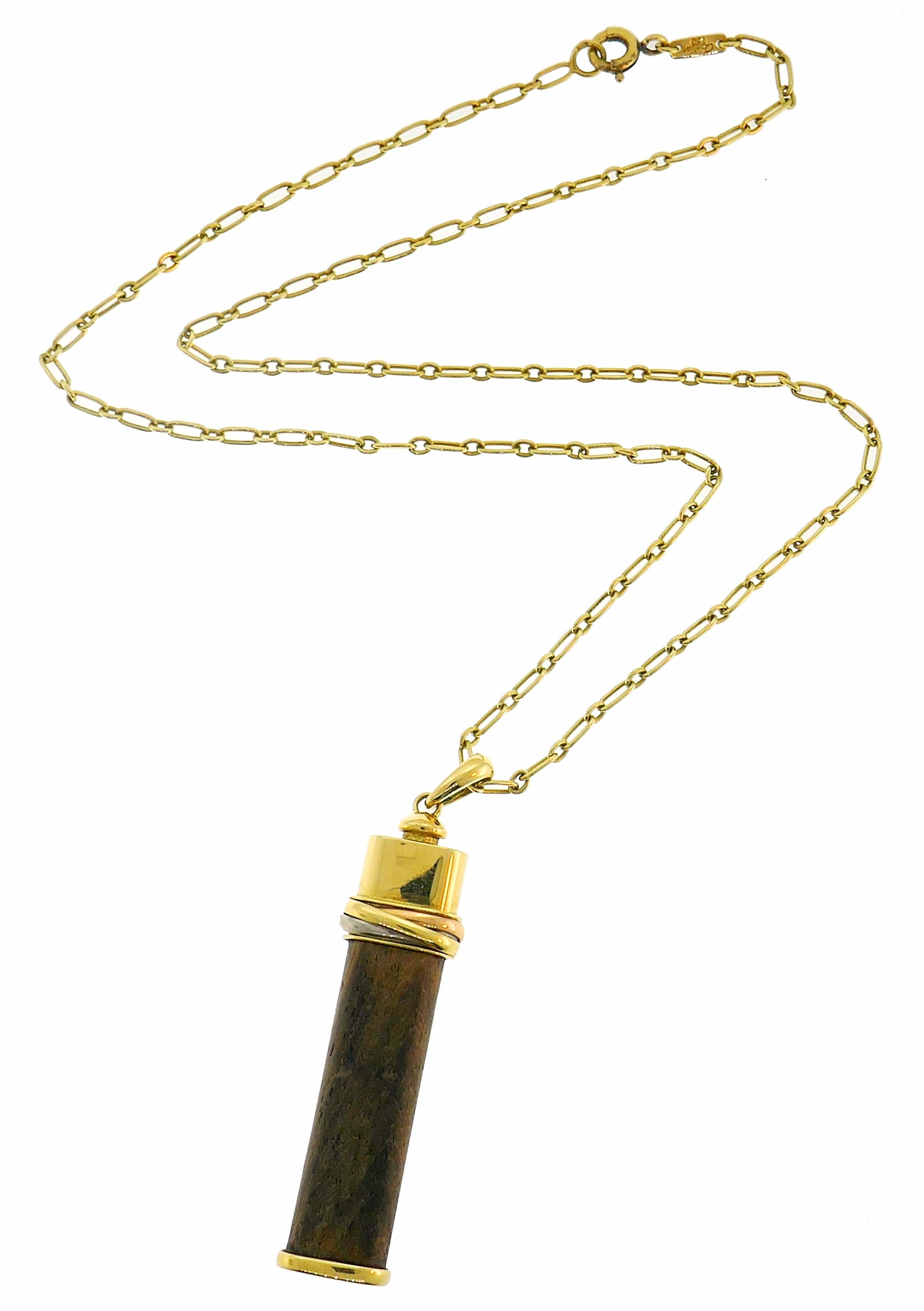 Signature Touch Wood pendant created by Cartier. Recognizable, It is made of 18 karat yellow, white and rose gold and wood. 
The pendant measures 1-3/4 x 3/8 x 1/4 inches (4.5 x 1.0 x 0.8 centimeters), the chain measures 18 x 1/16 inches (45 x 0.2